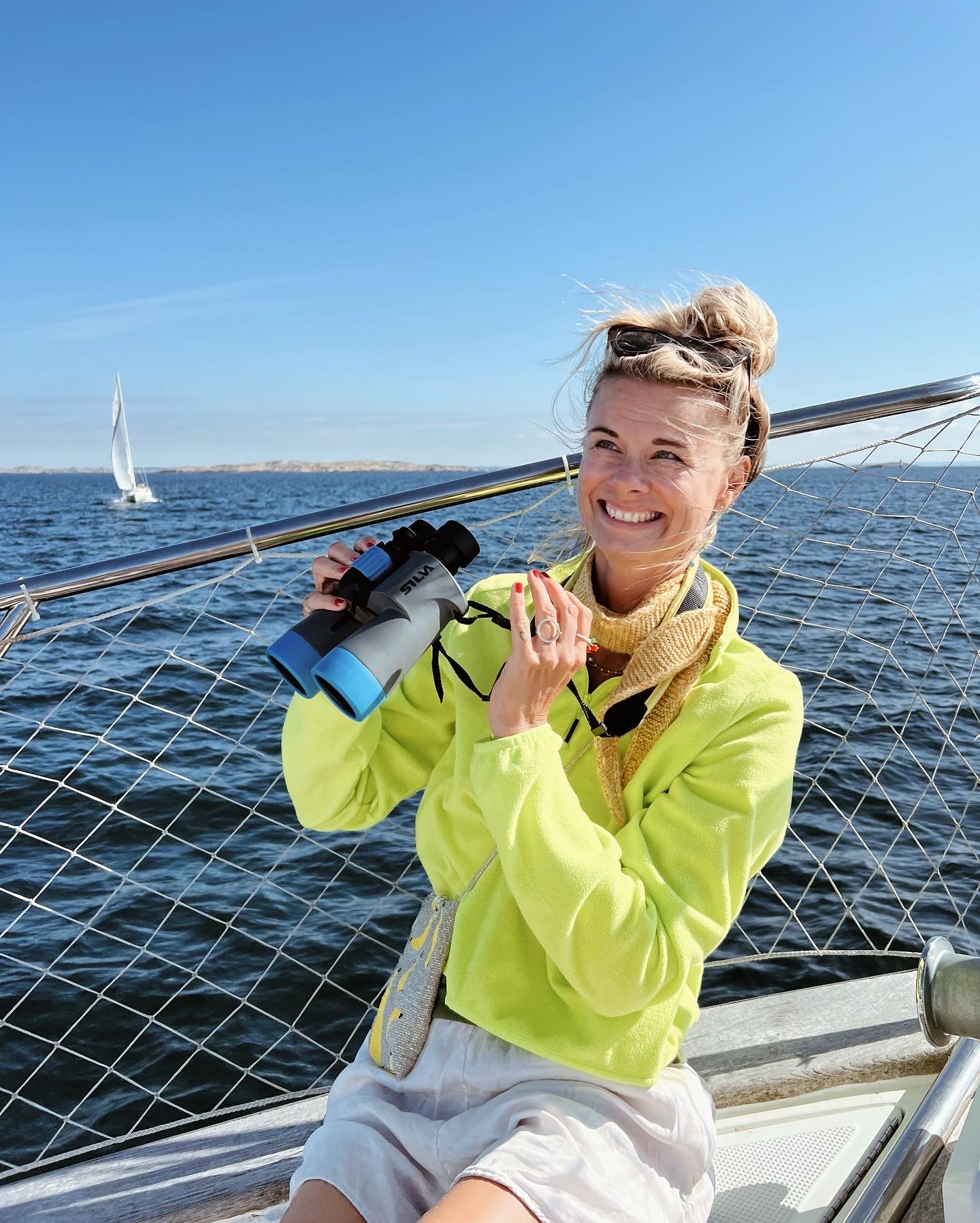 Trine is holding binoculars on the boat