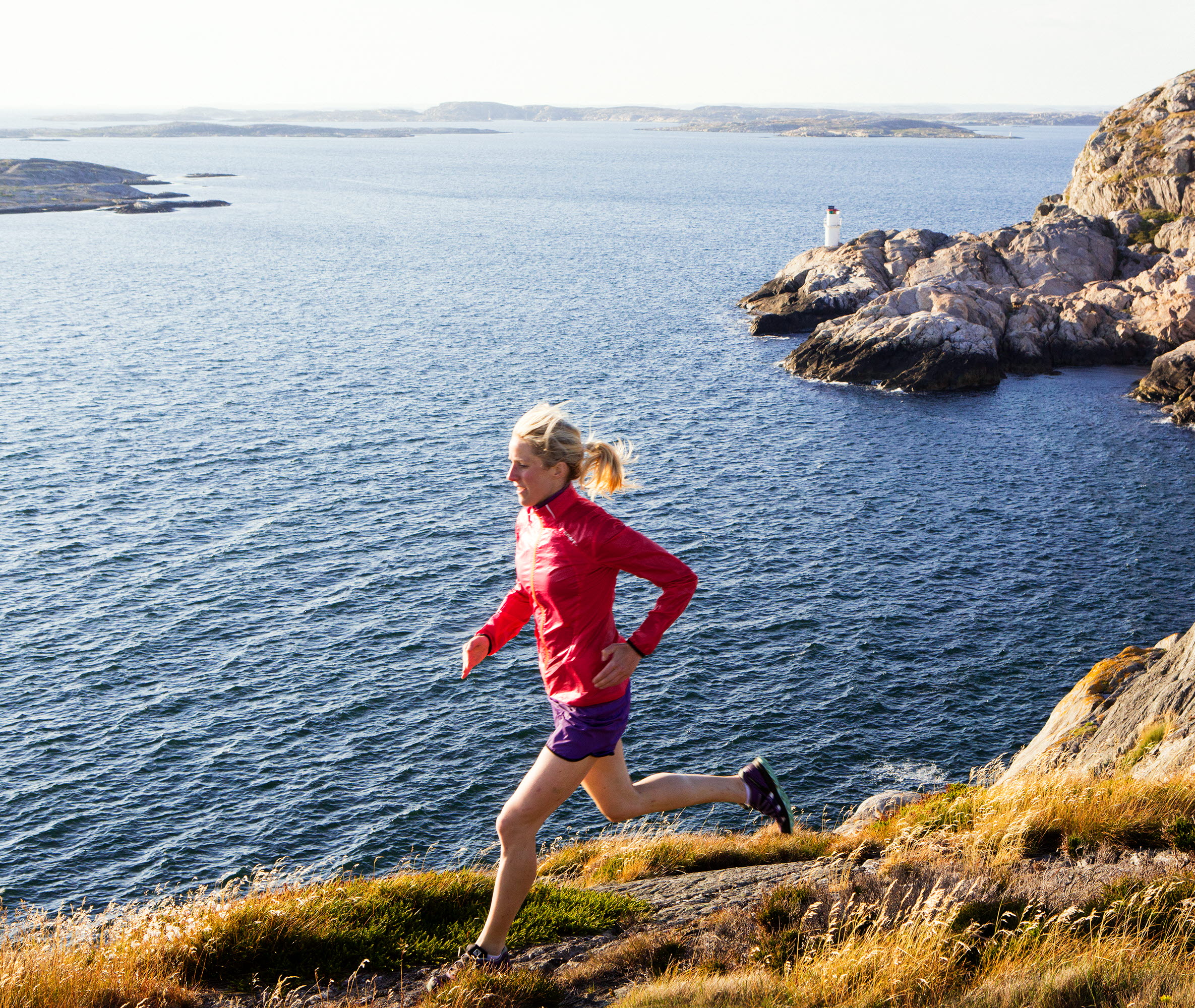 Kvinna springer på klippor utmed vattnet