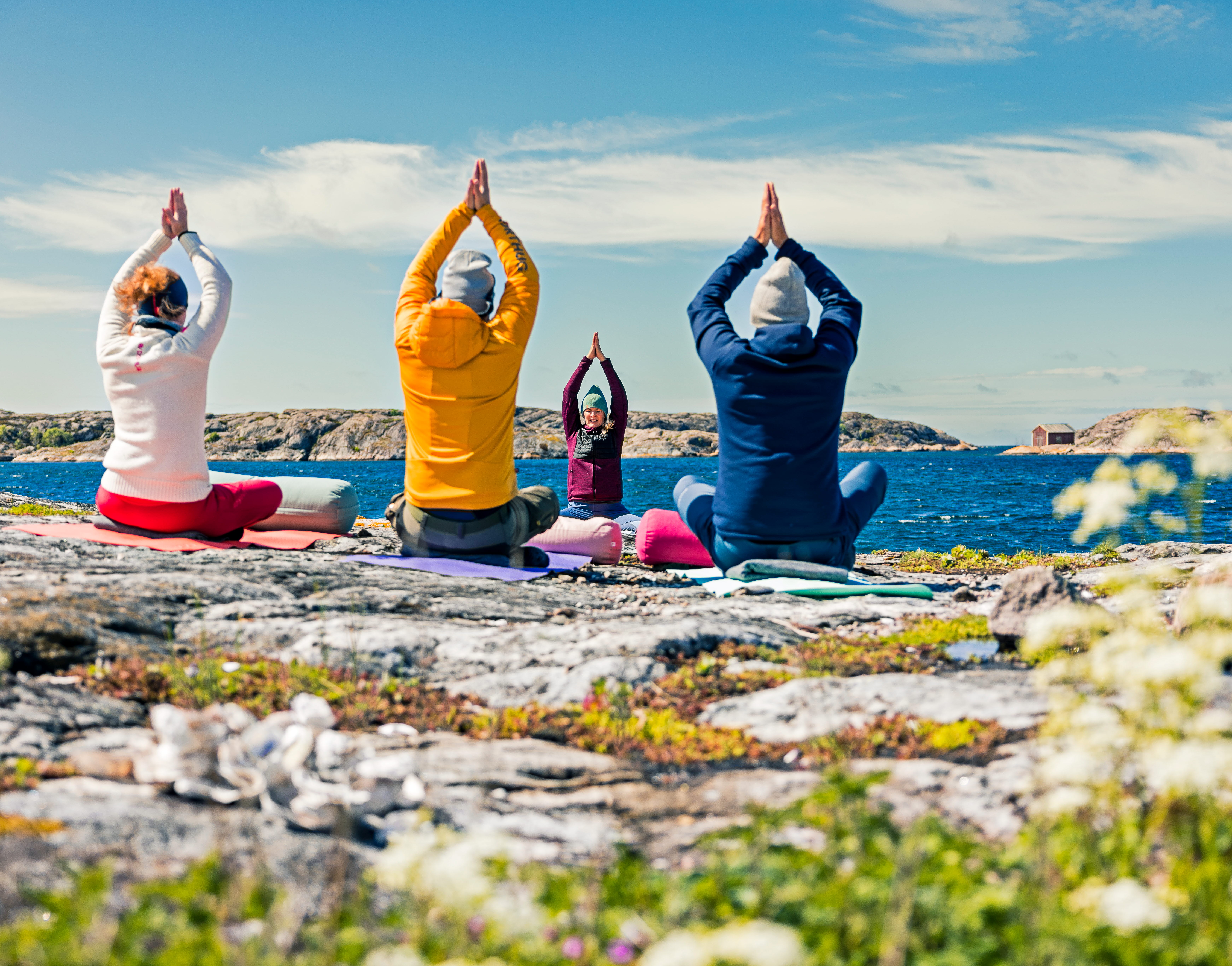 A group of people practicing yoga outdoors on the coast.