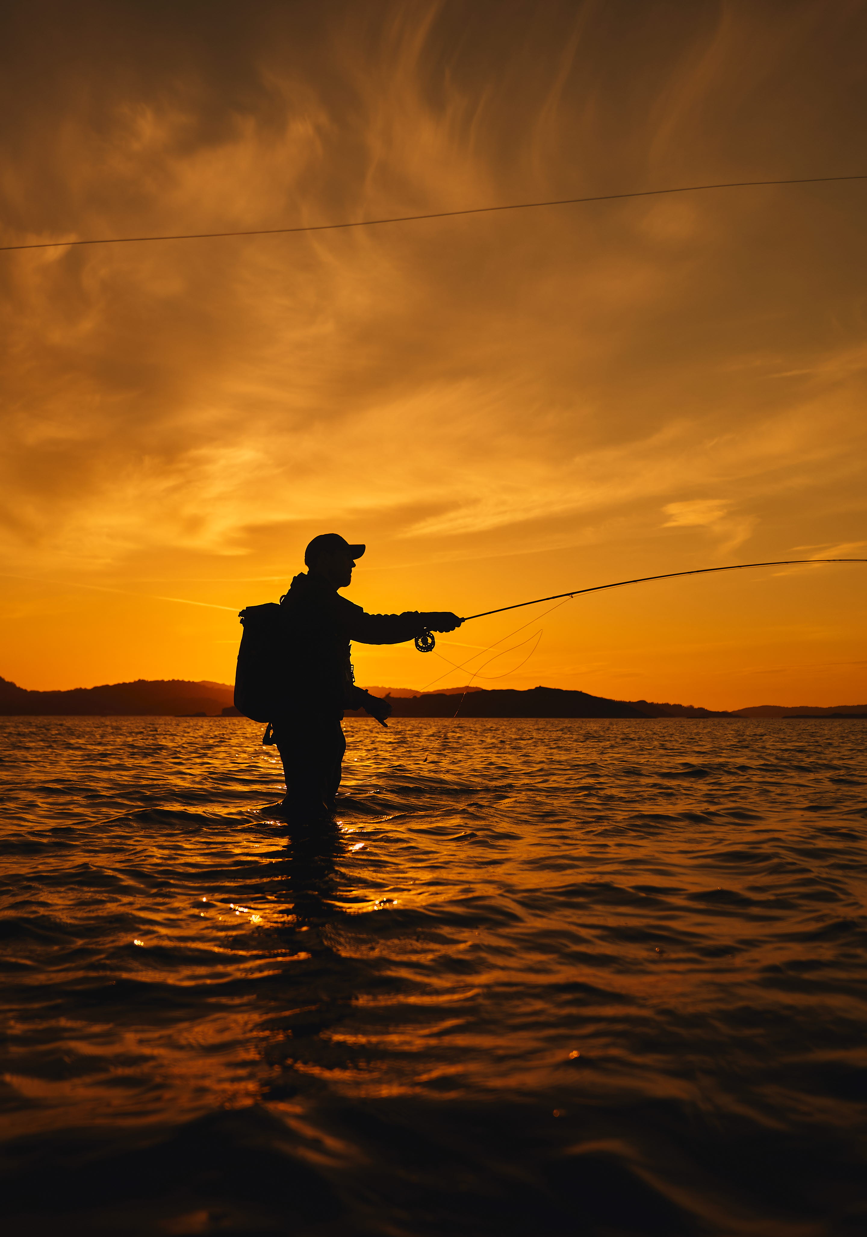 En man står i havet och fiskar.
