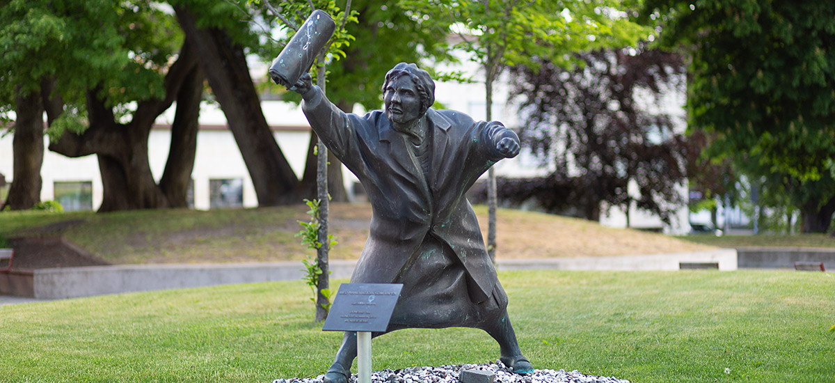 Staty på dam med handväska i luften