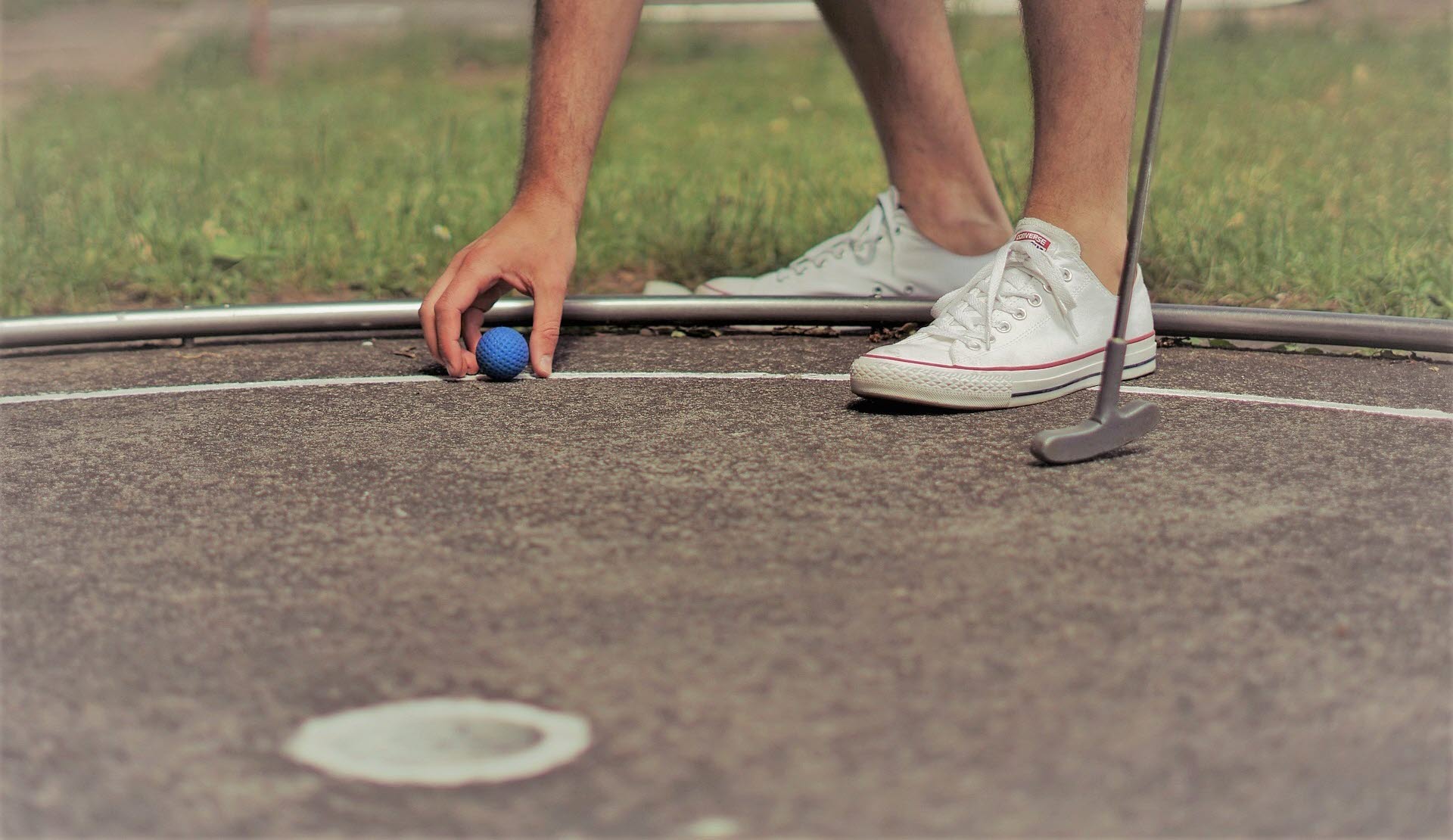 Man på minigolfbana med klubba och boll. 