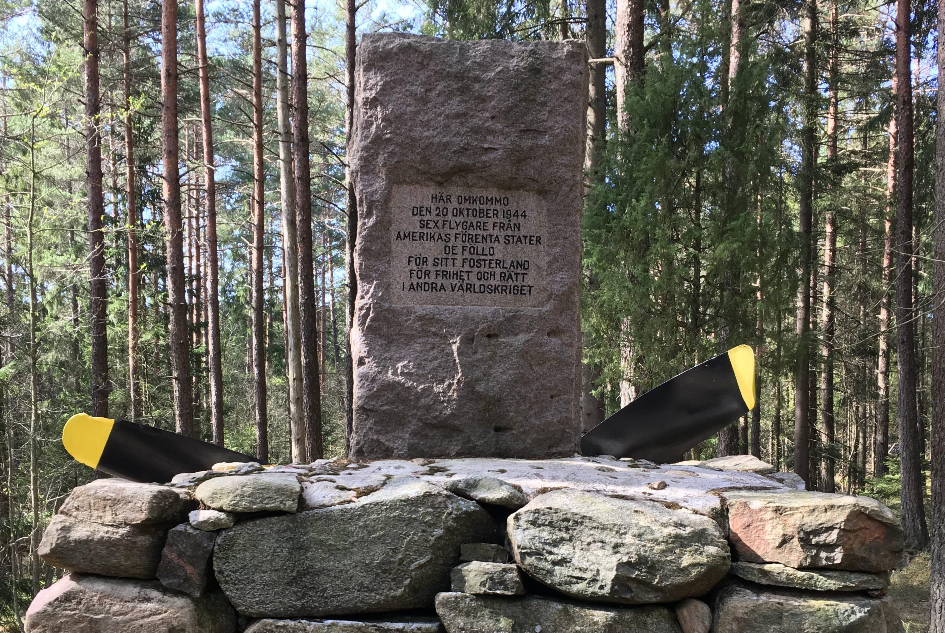 Infosten i skogen med ett stenblock. 
