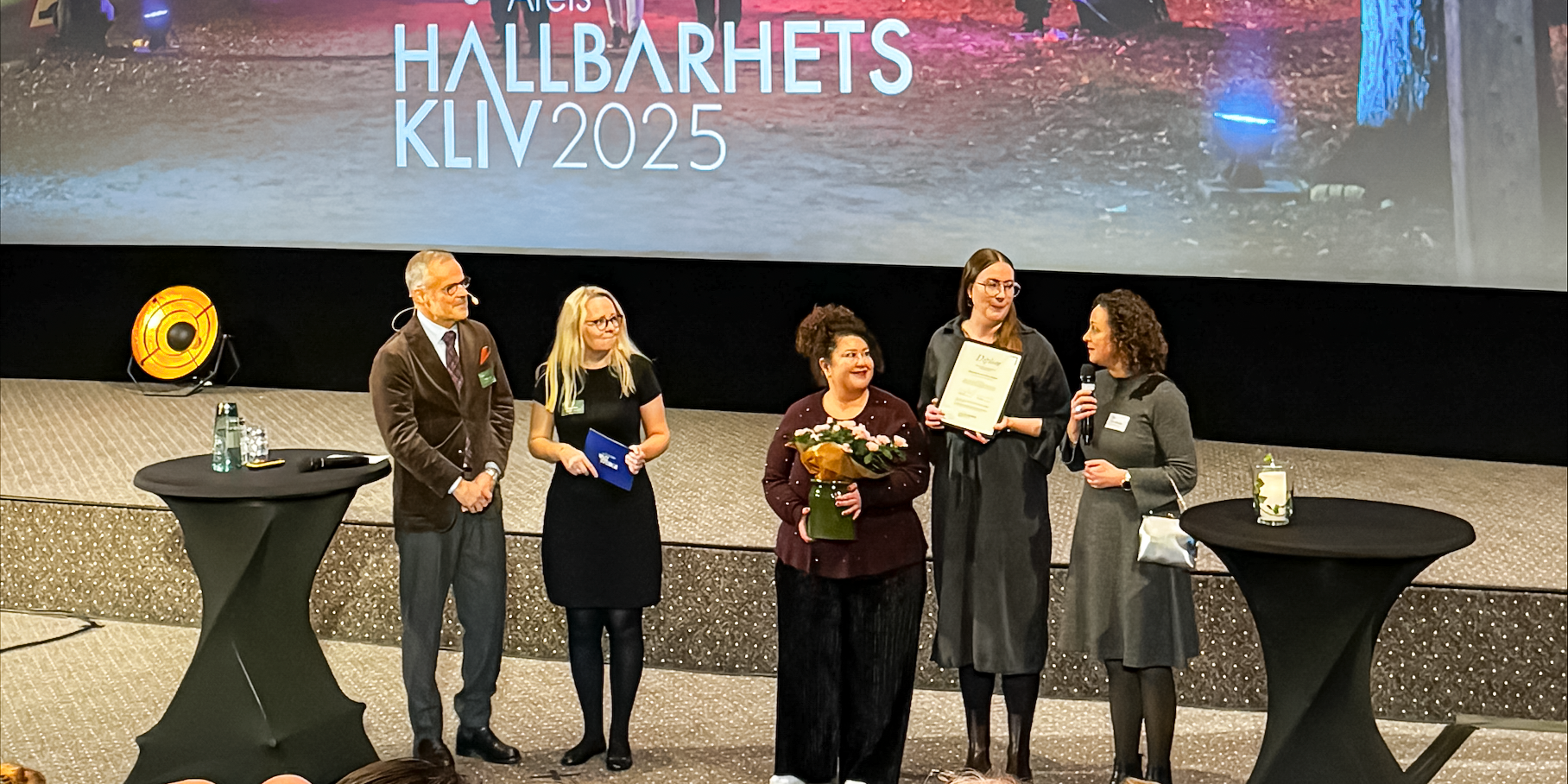 Fem personer som står på en scen.