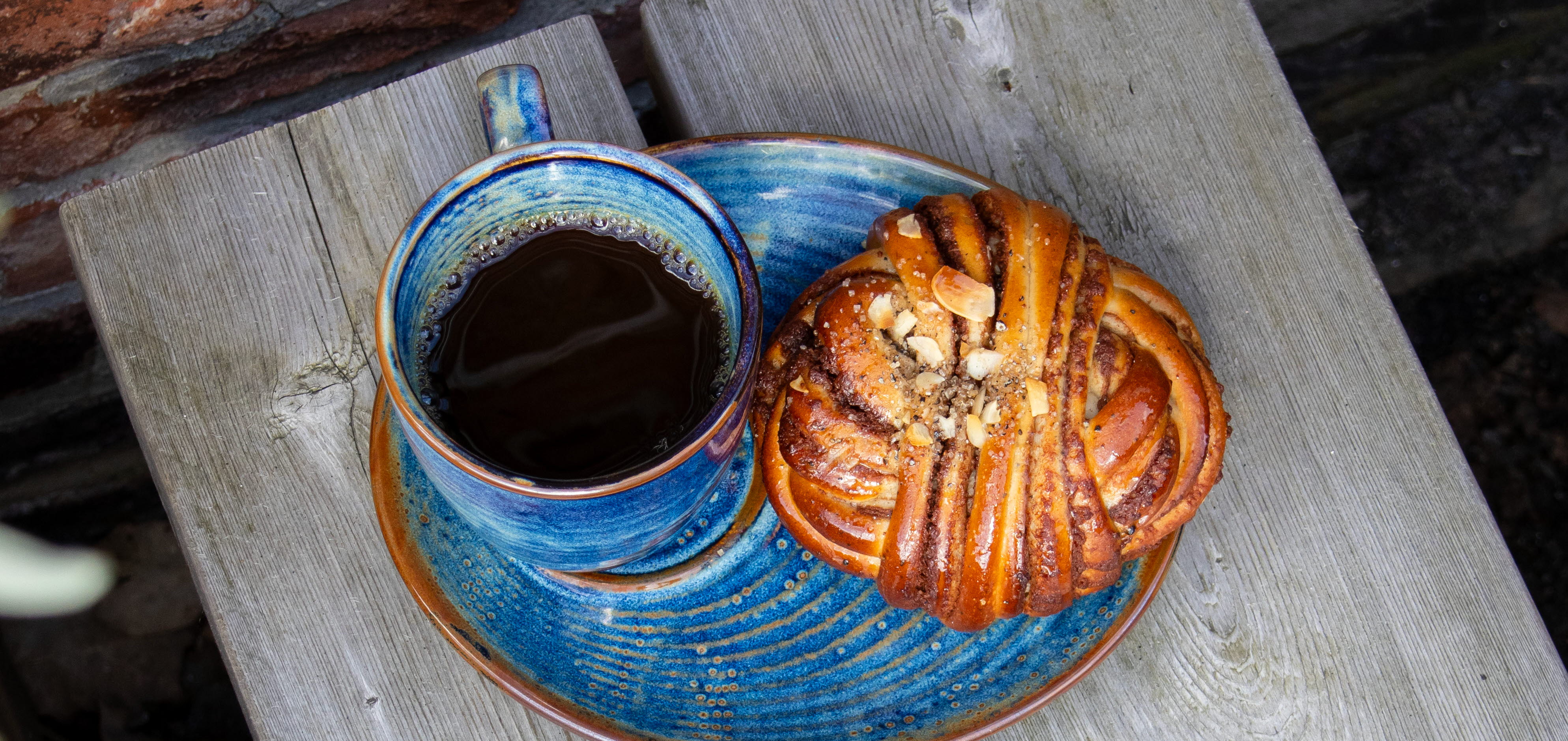 Blå fat med bullar och en blå kaffekopp med kaffe i.