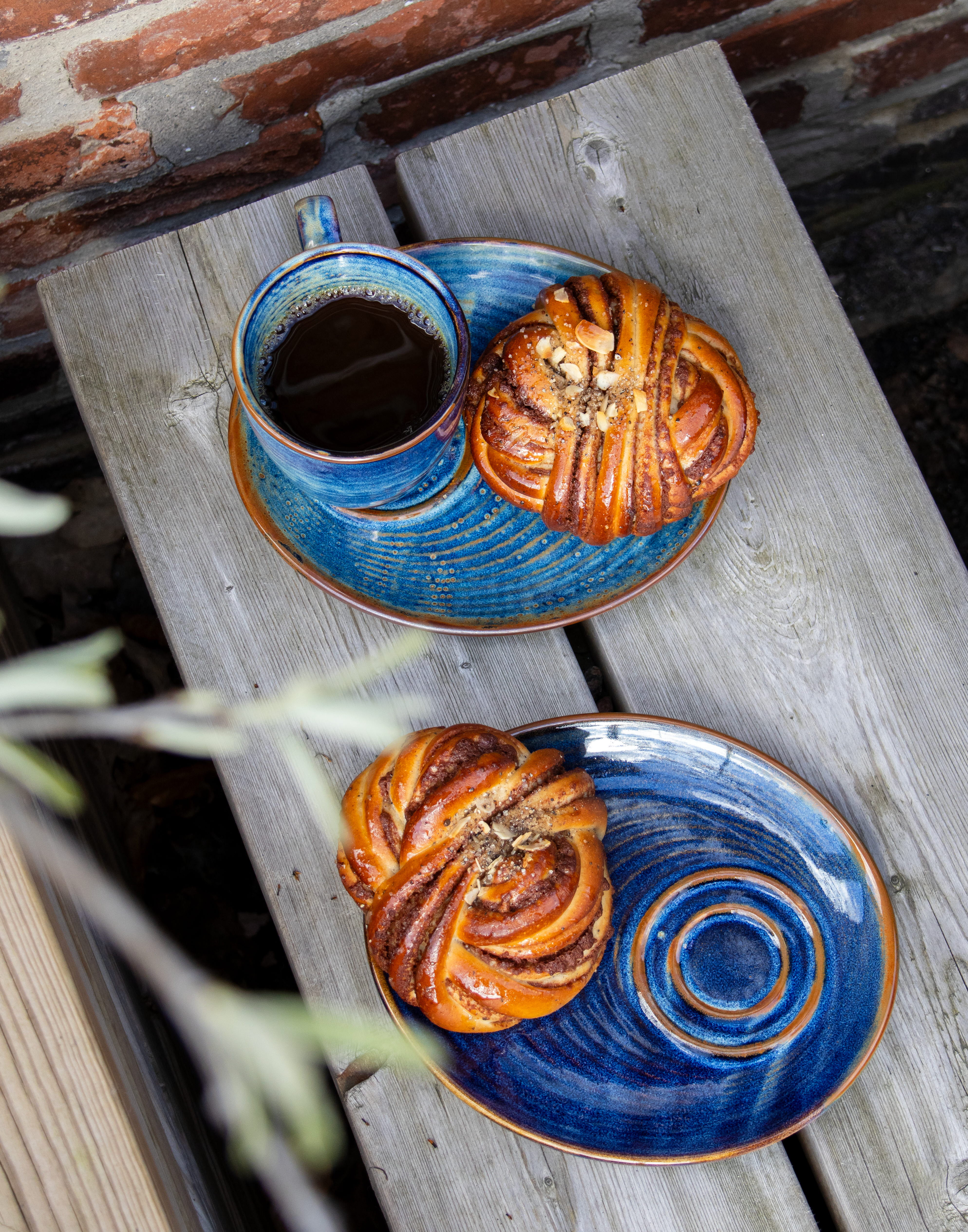 Blå fat med bullar och en blå kaffekopp med kaffe i.