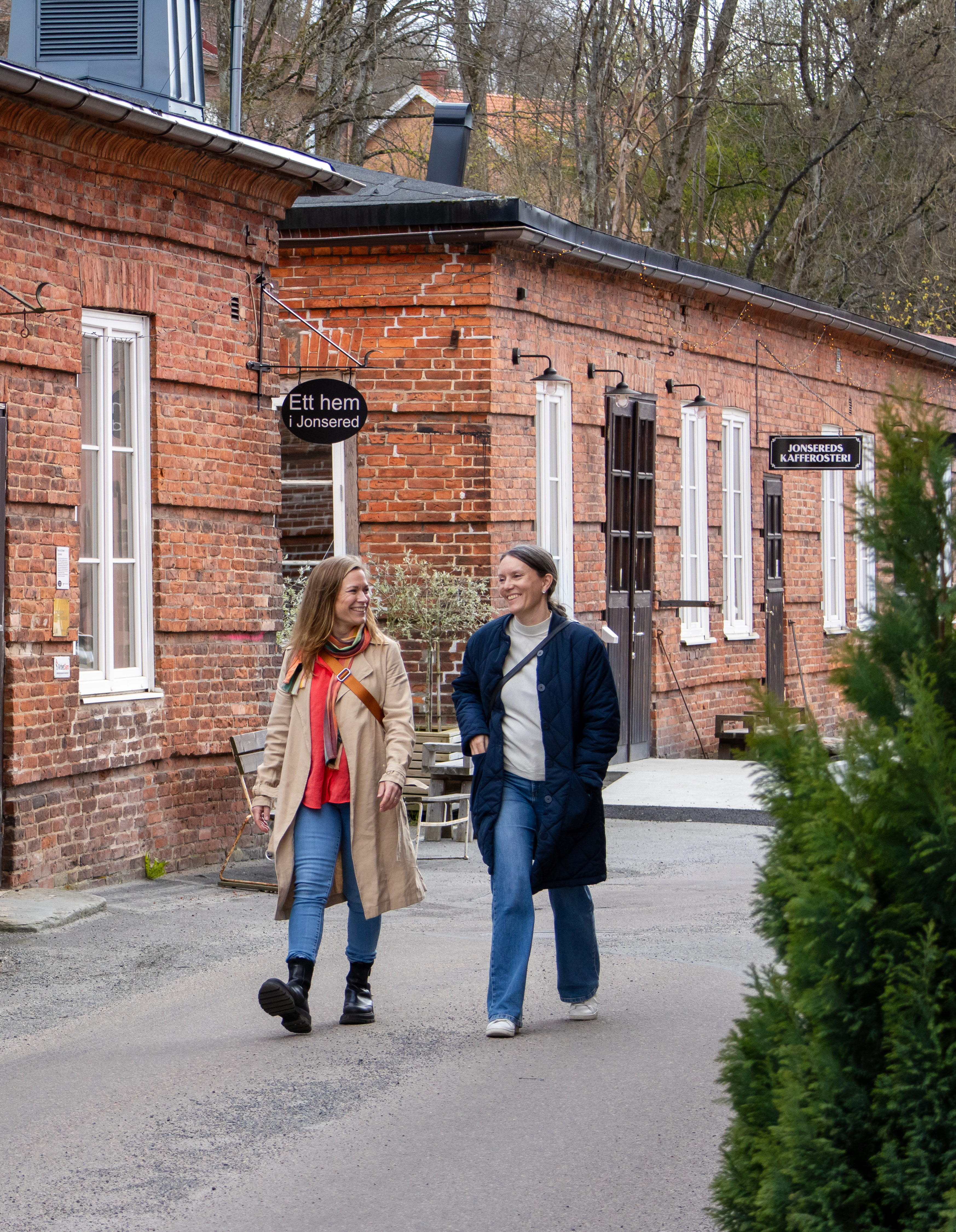 Två kvinnor går i en gammal bruksmiljö.