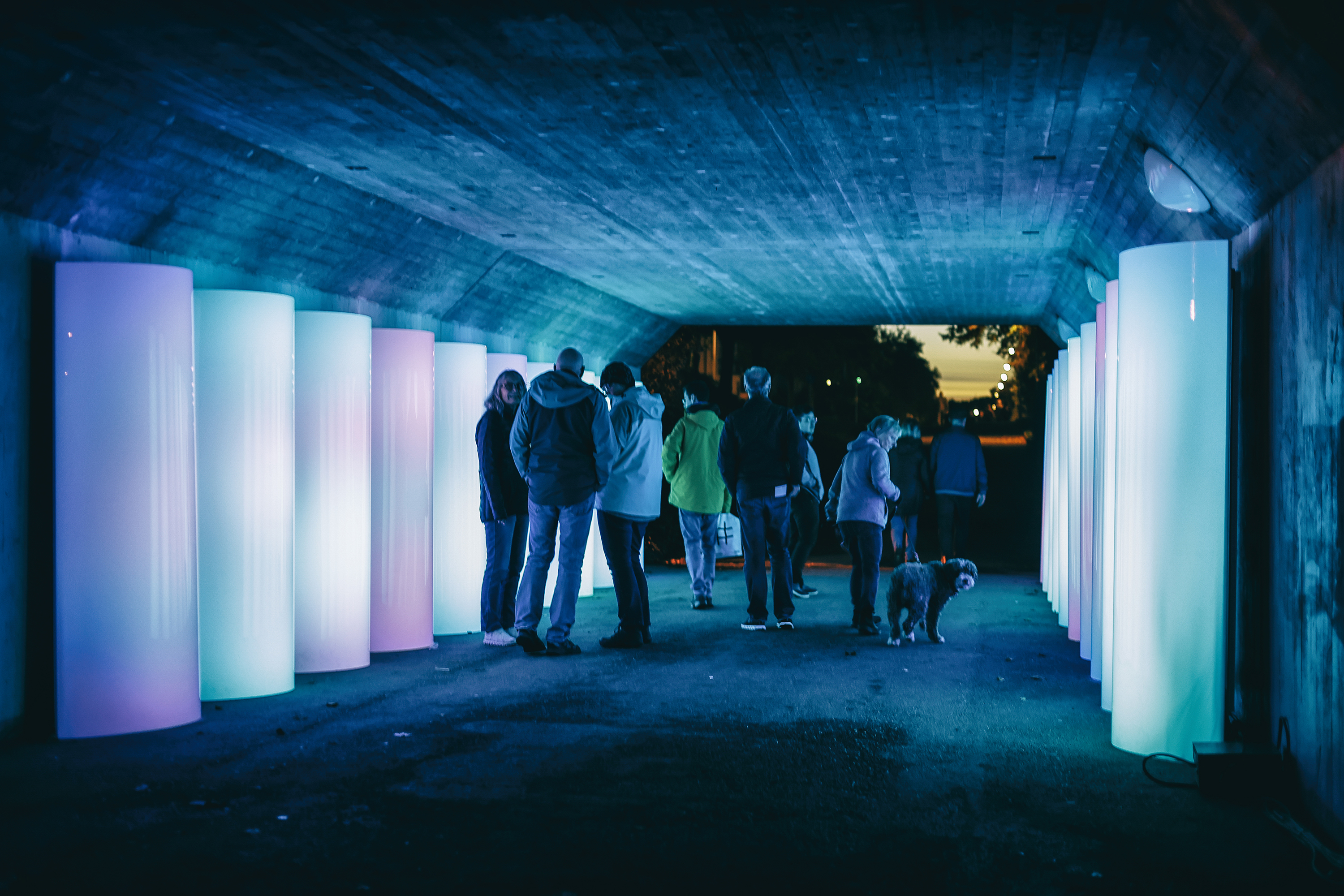 Personer som står i en upplyst gångtunnel.