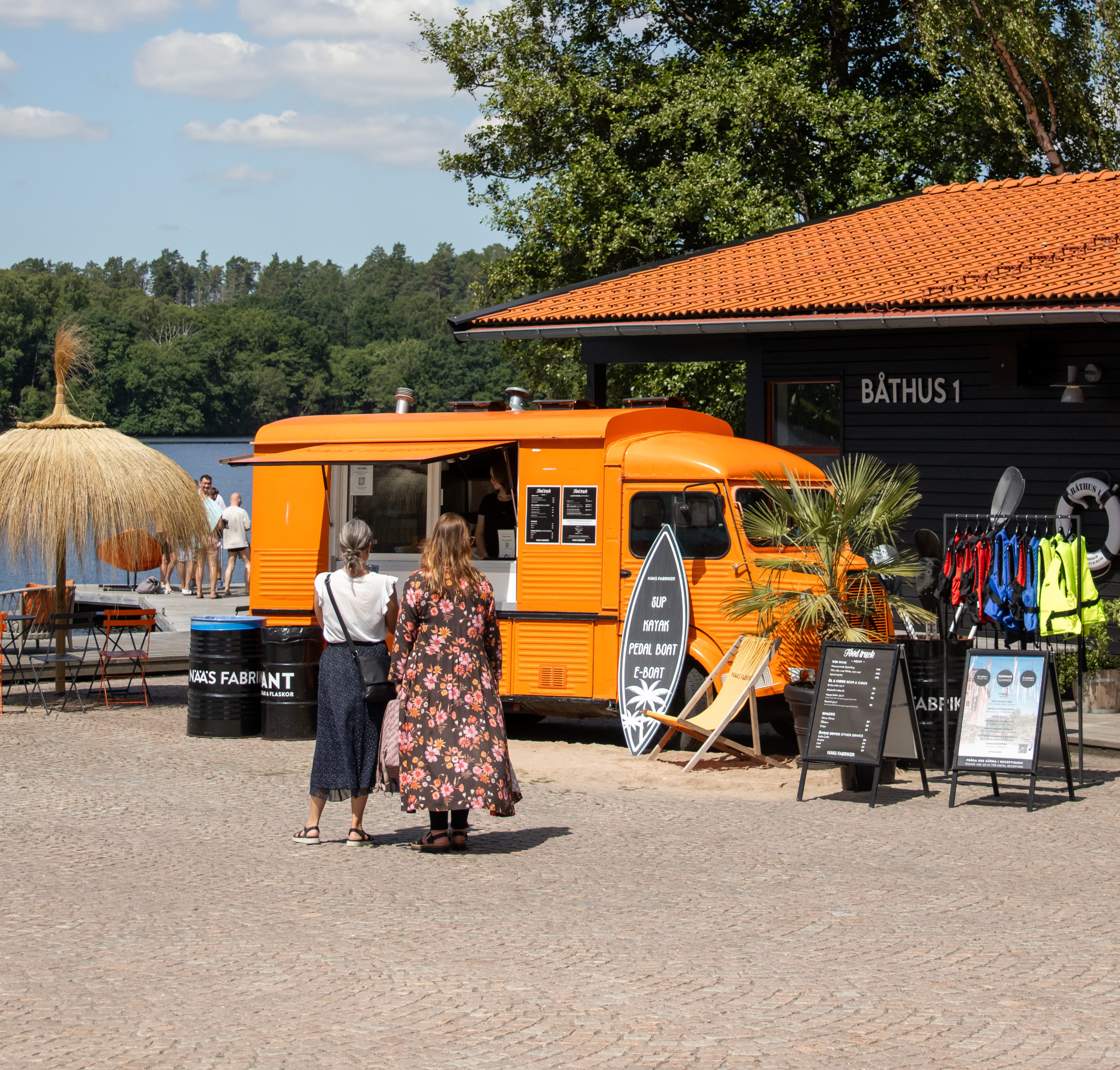Två kvinnor som går mot ett orangegult fordon som fungerar som serveringslucka.