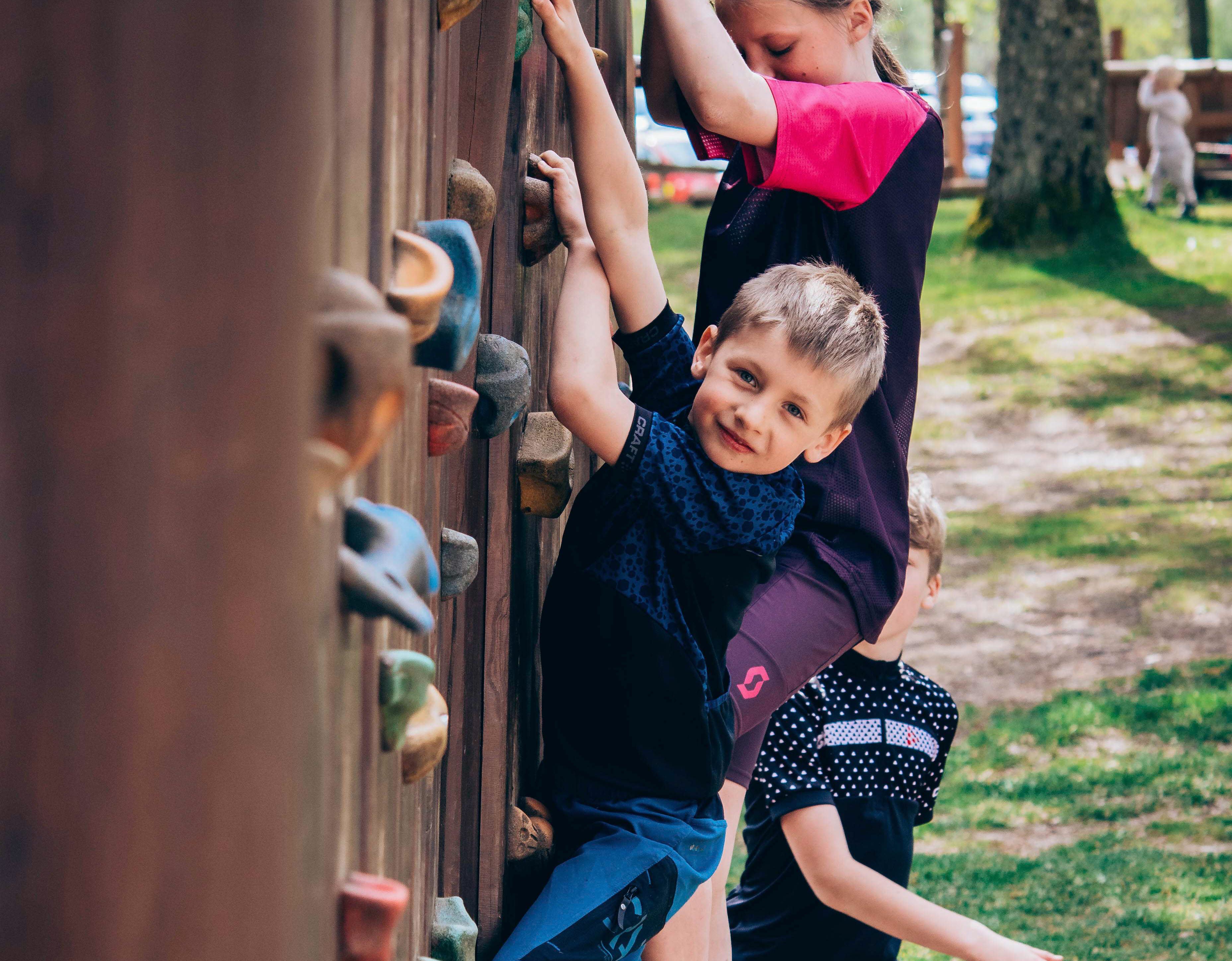 Glad kille som klättrar på klättervägg