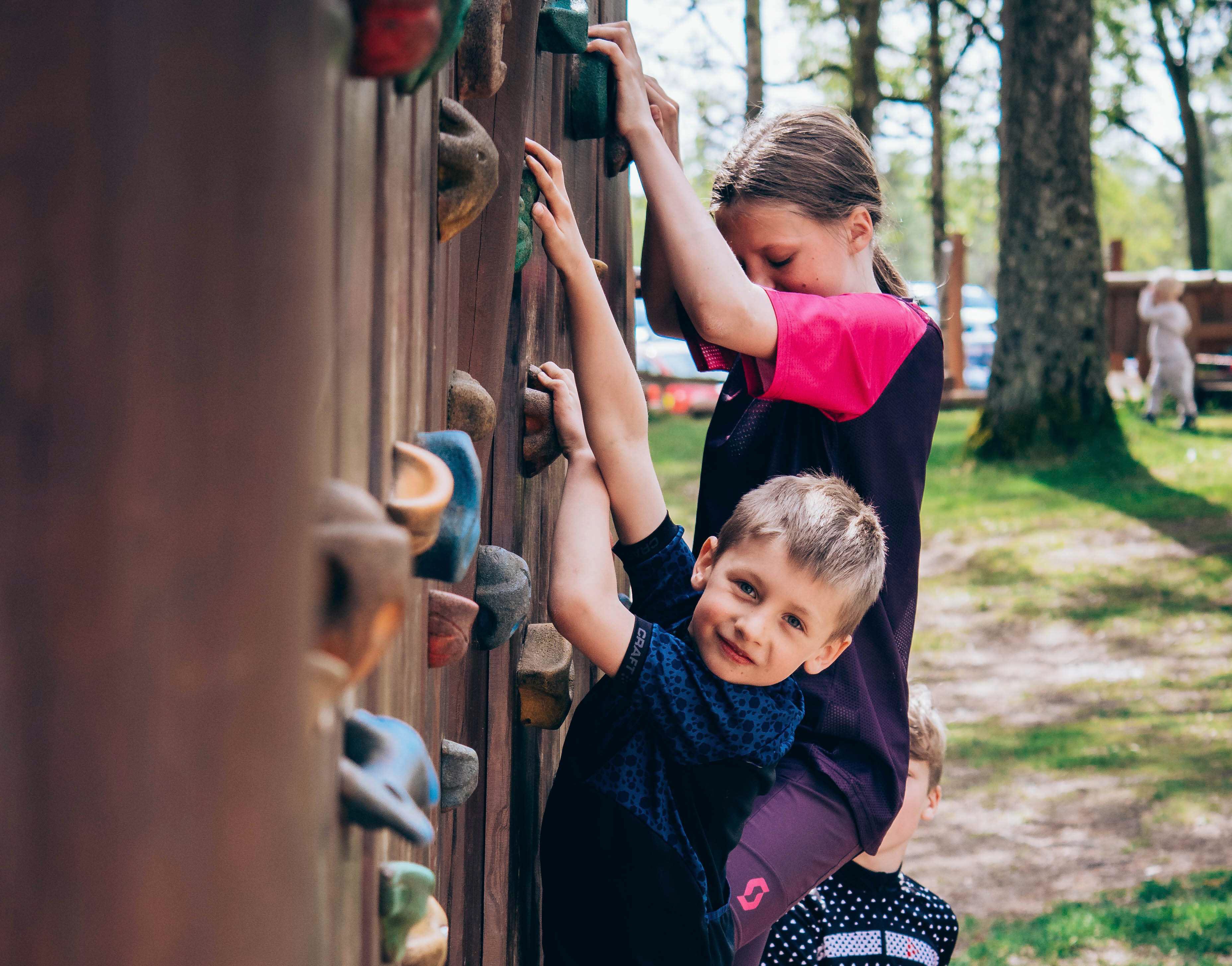 Glad kille som klättrar på klättervägg
