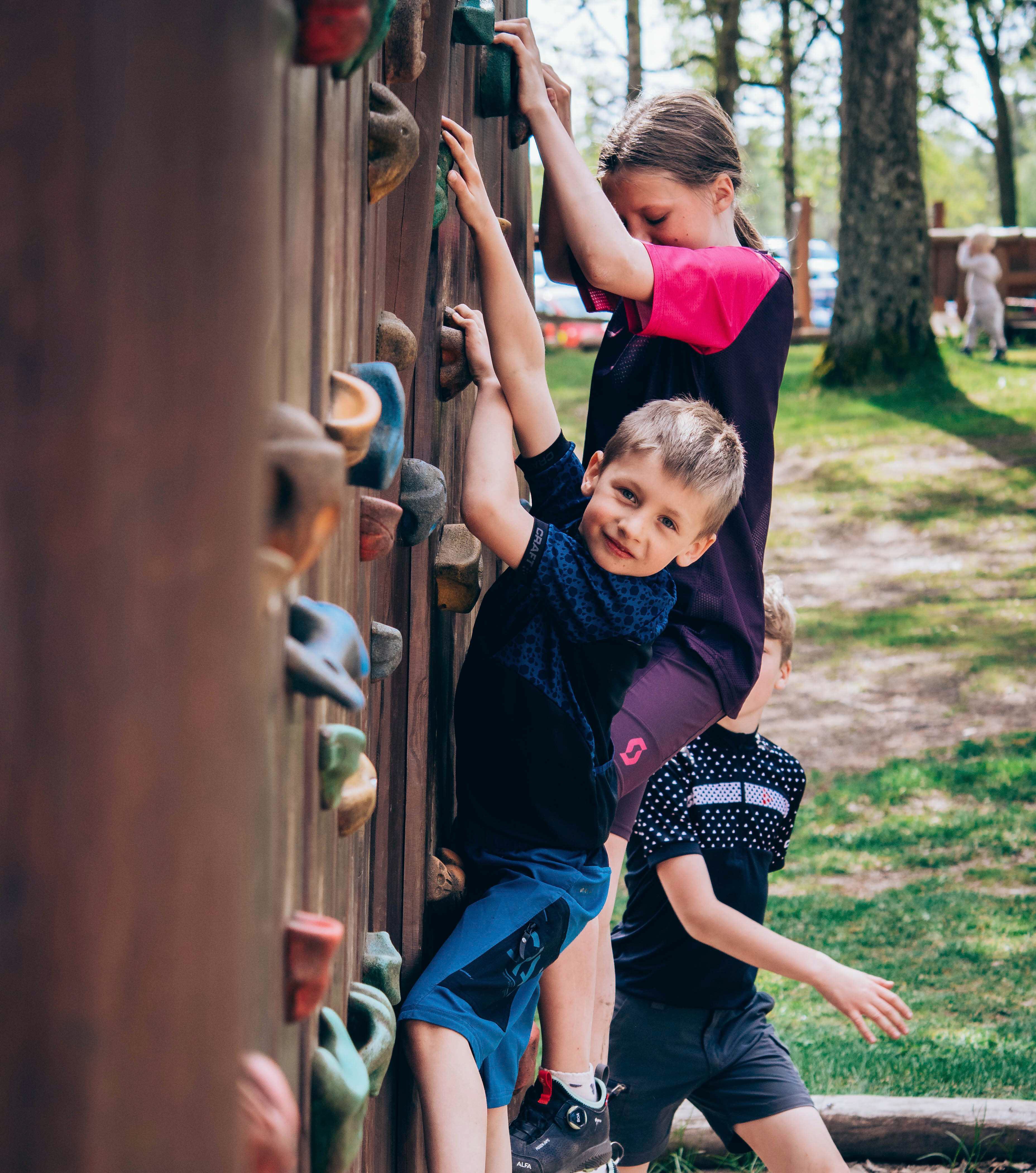 Glad kille som klättrar på klättervägg
