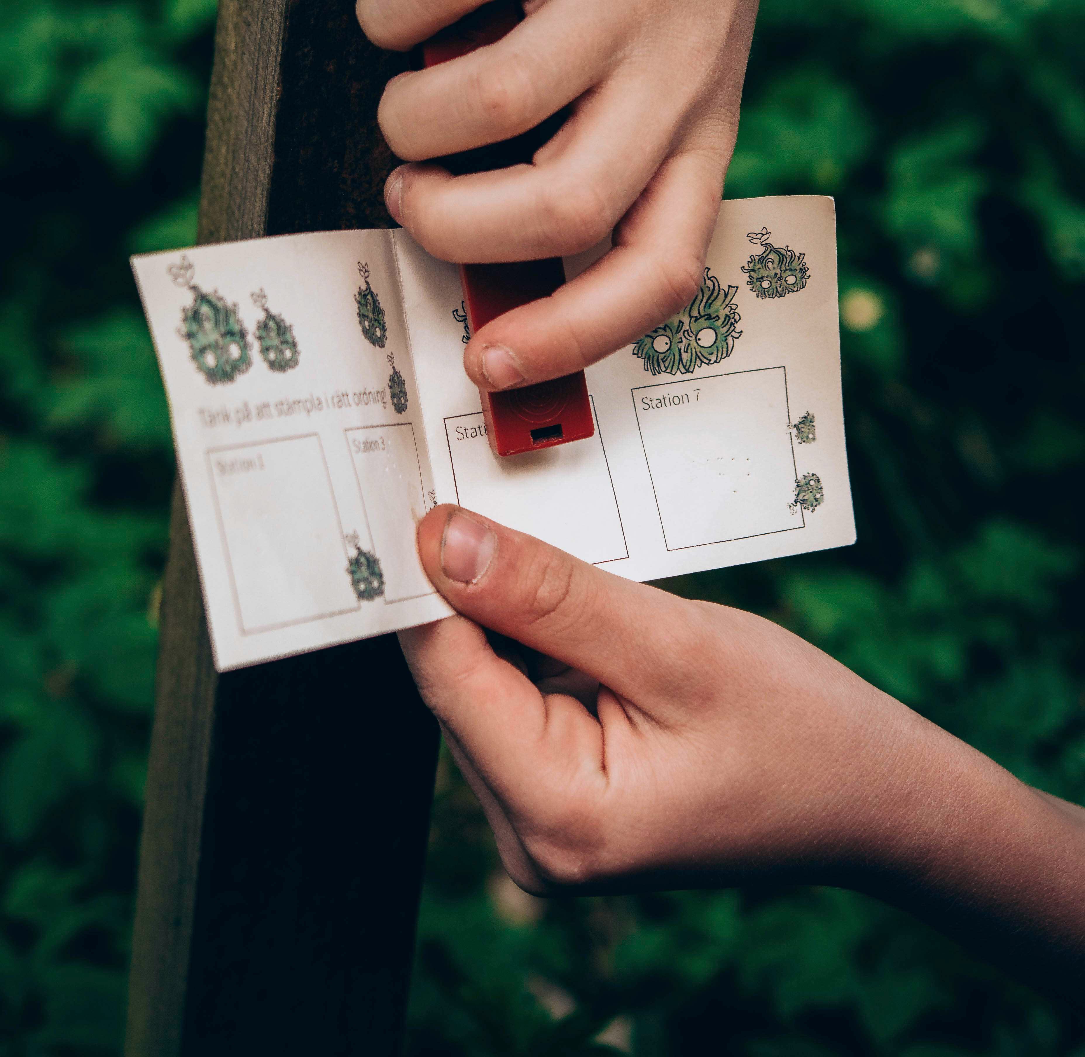 Händer som stämplar ett orienteringspass (utmed Billingetrollets trollstig)