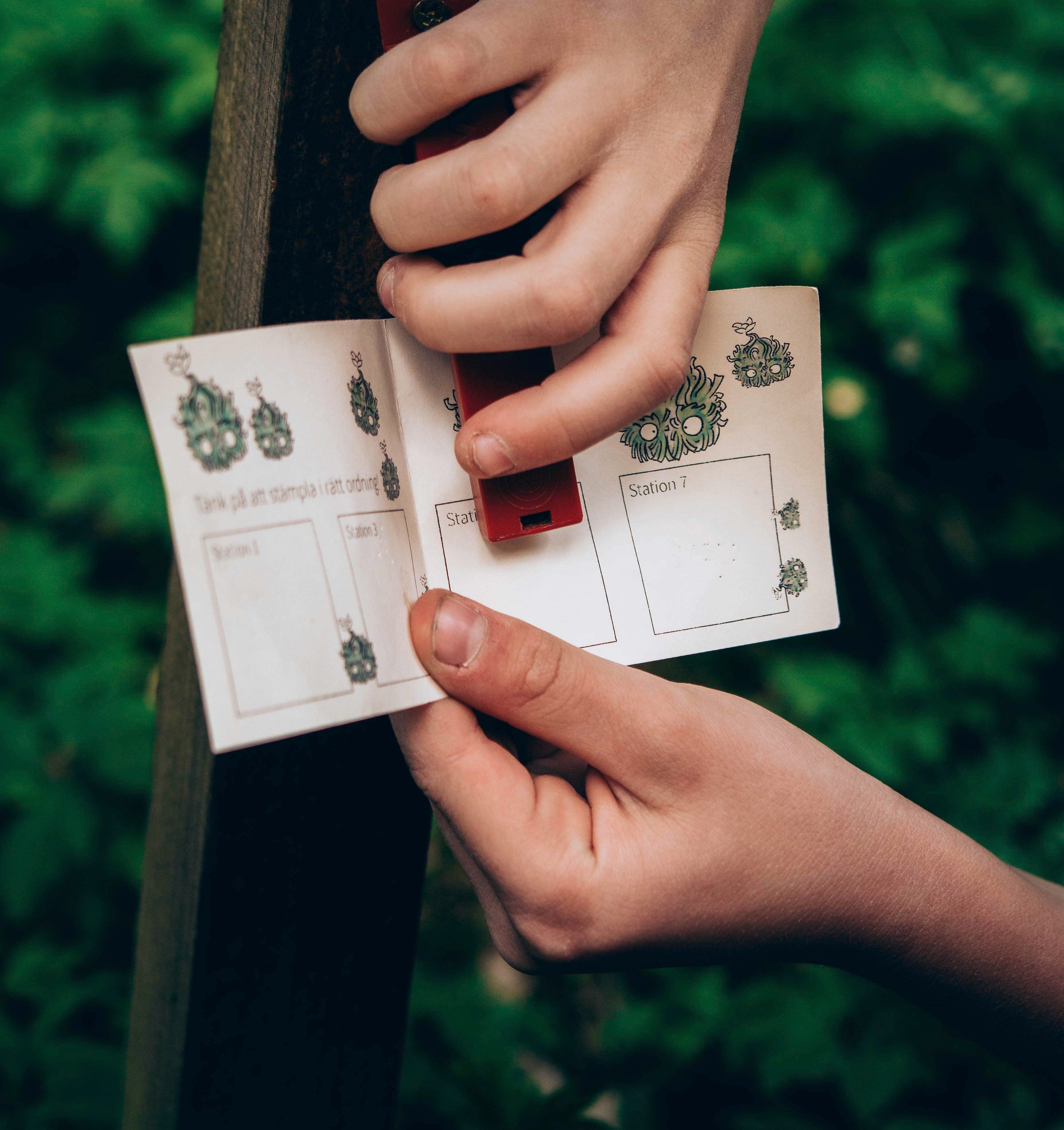 Händer som stämplar ett orienteringspass (utmed Billingetrollets trollstig)