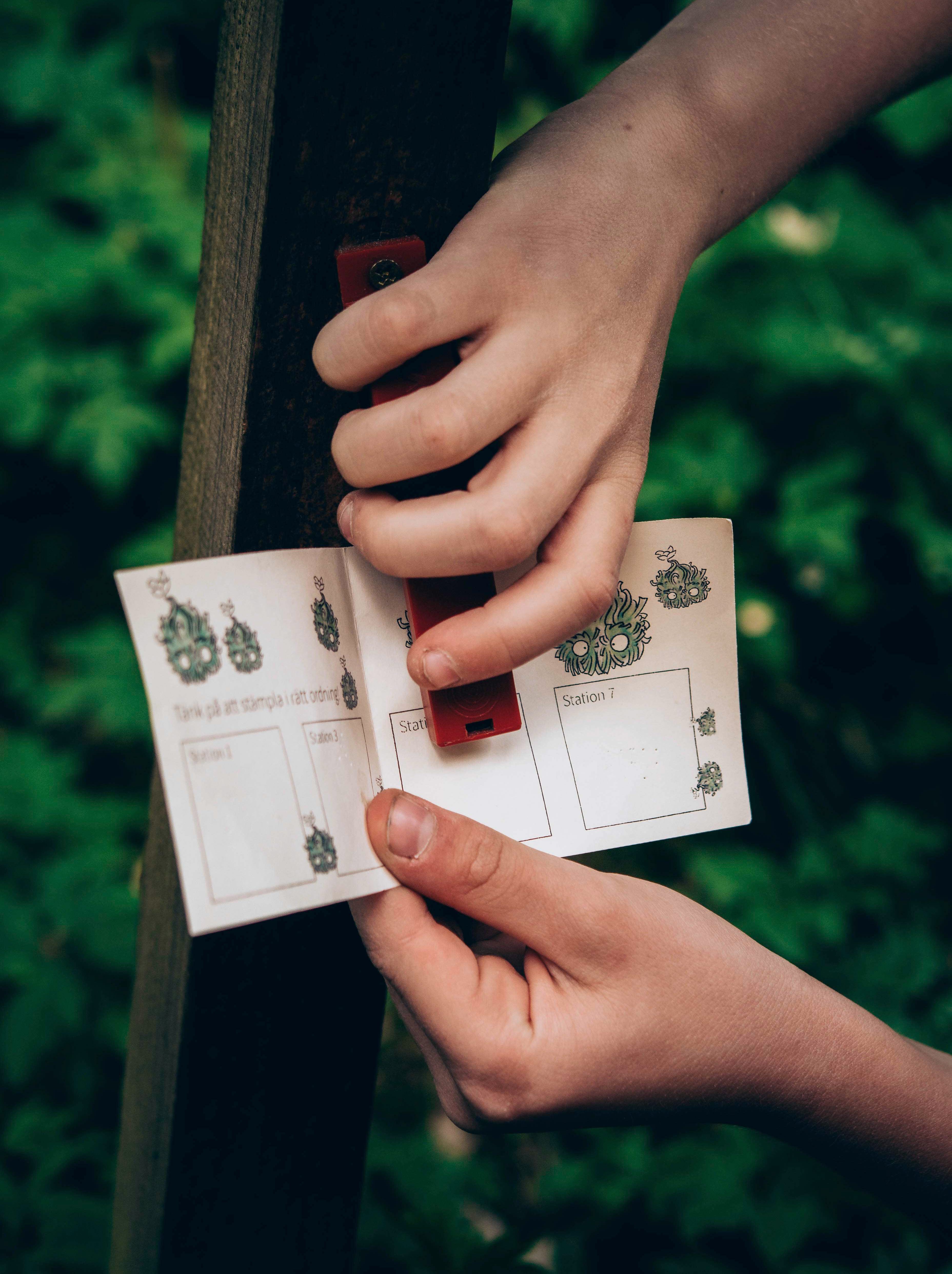 Händer som stämplar ett orienteringspass (utmed Billingetrollets trollstig)
