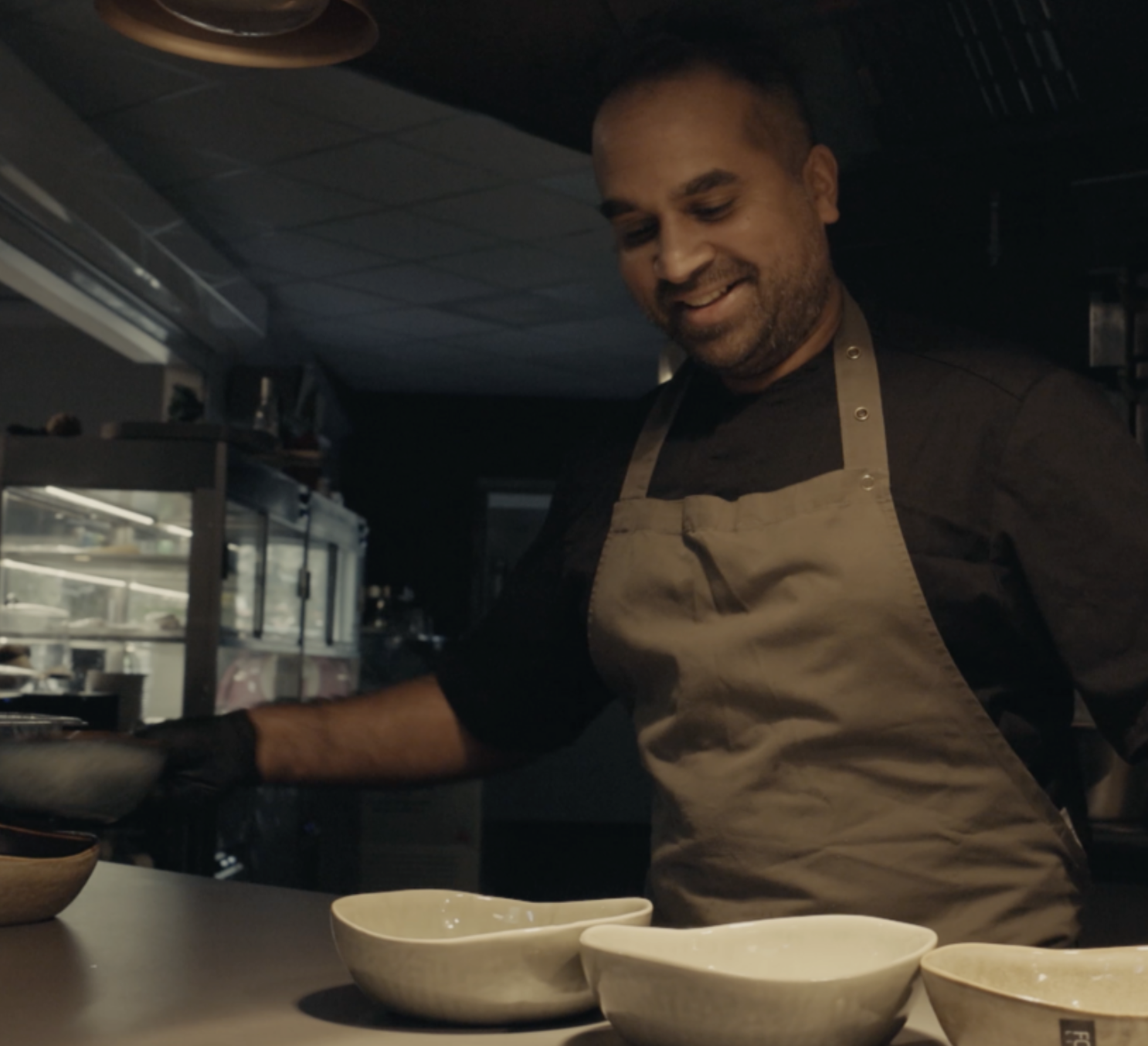 Chef with an apron and gloves in front of him, he has plates