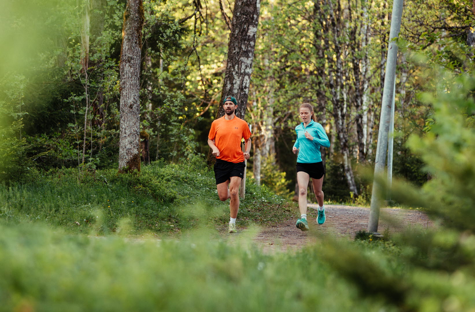 Två personer som springer längs ett motionsspår i skogen.