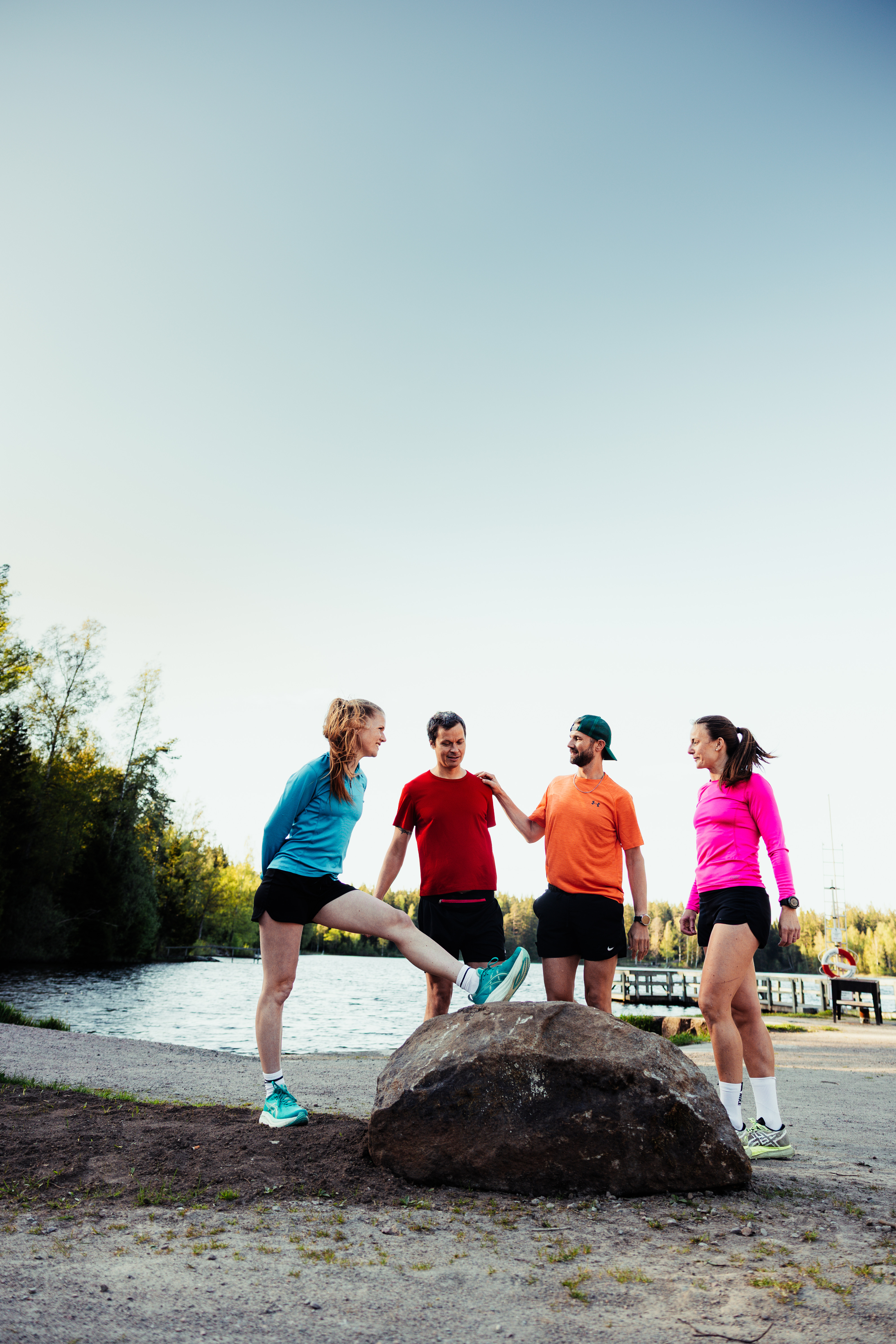 Fyra personer som står vid en sten och stretchar