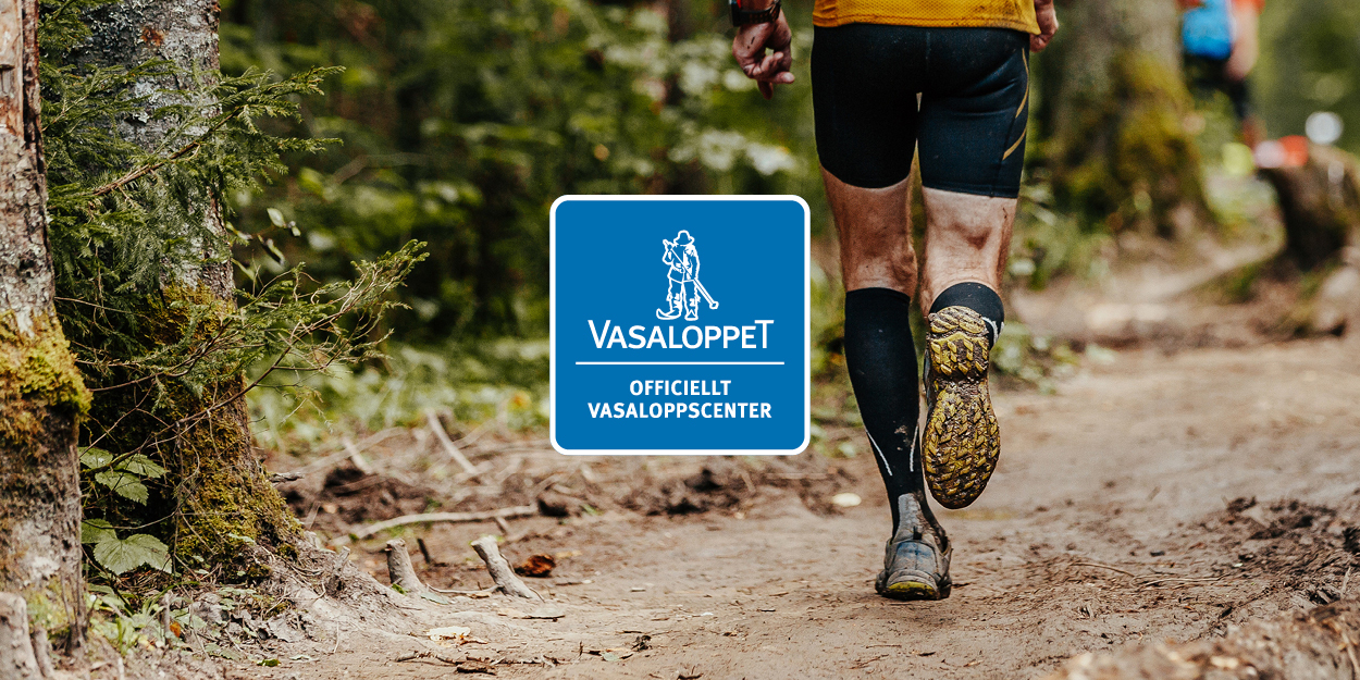 En person springer genom skogen. På en blå logotyp står det Vasaloppet - Officiellt Vasaloppscenter