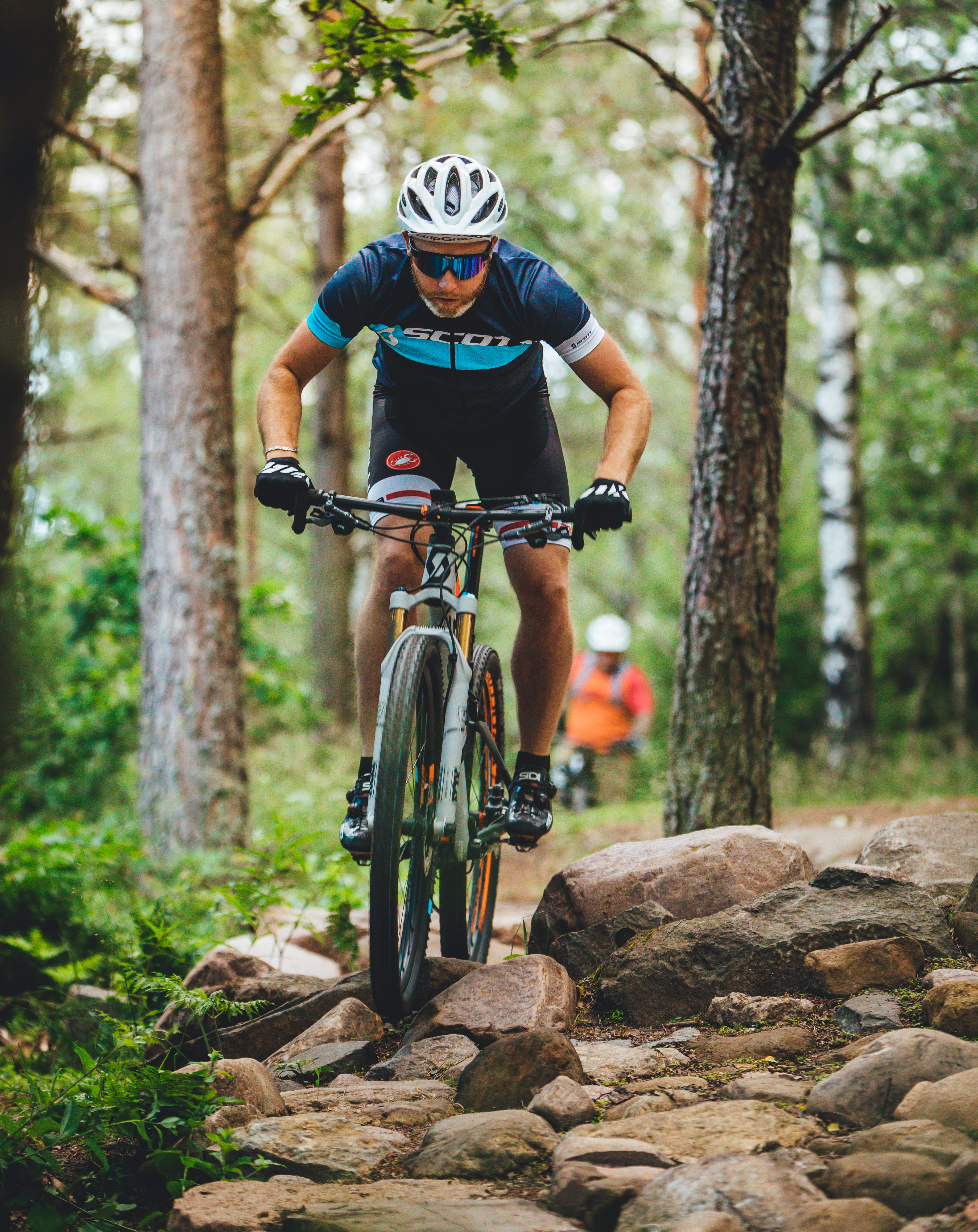 Man cyklar med mountainbike över stenar i skogen