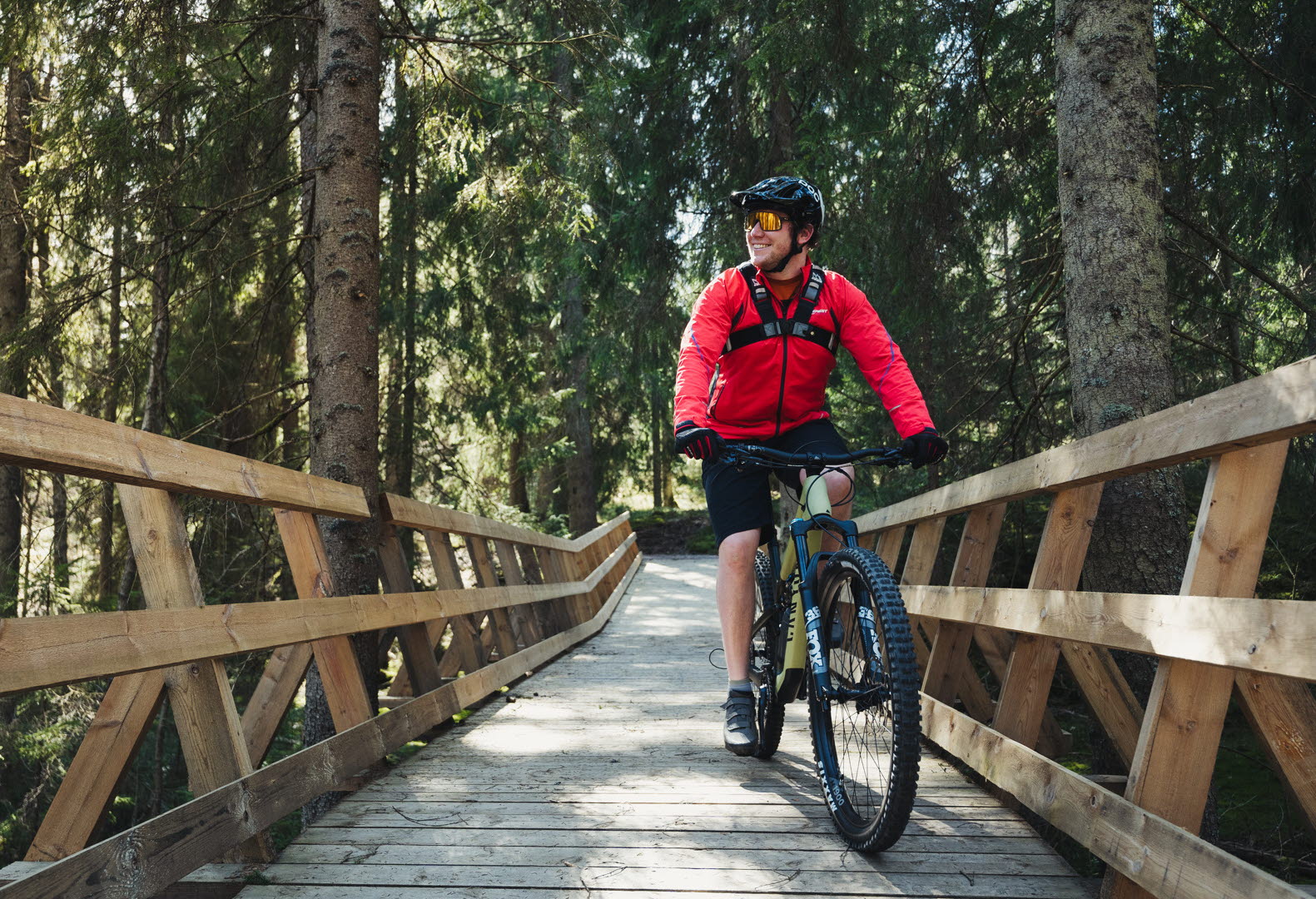 You ride a mountain bike on a wooden bridge built in the forest