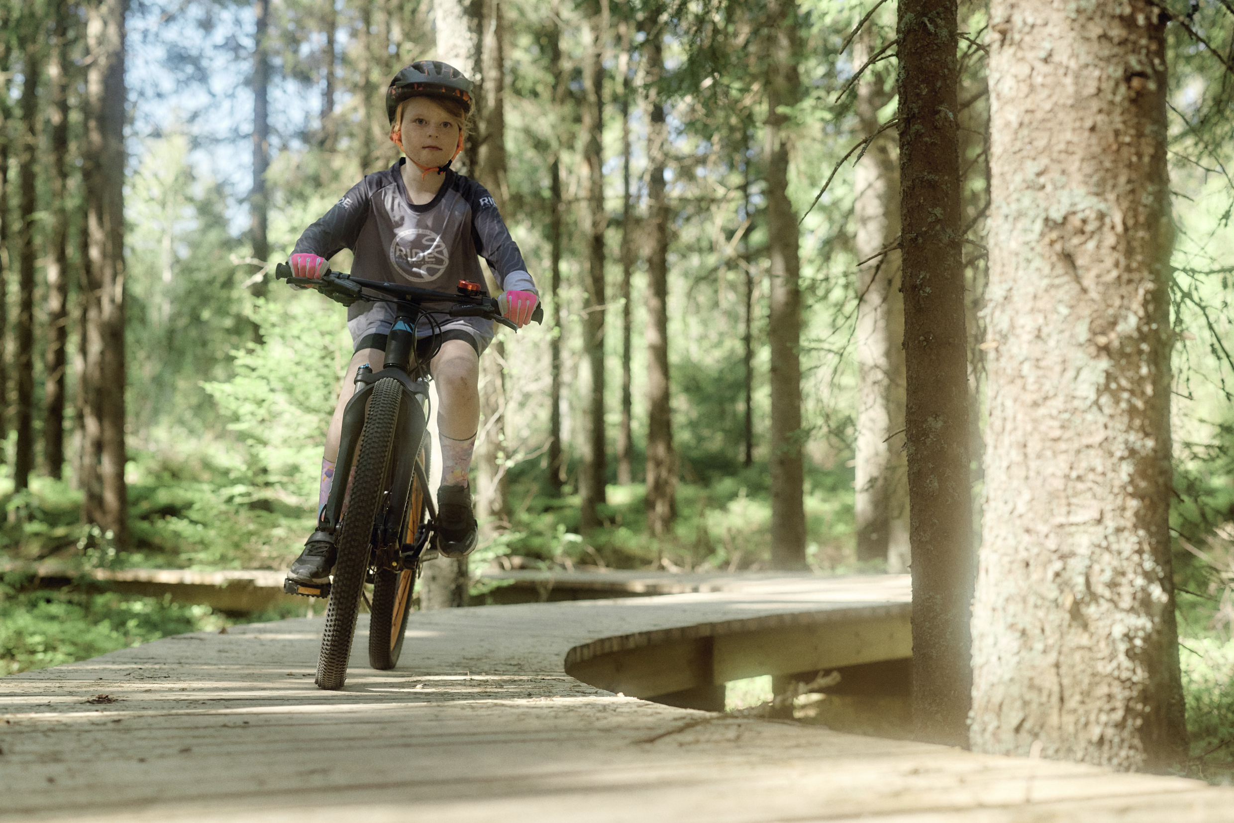 En flicka cyklar längs en träväg