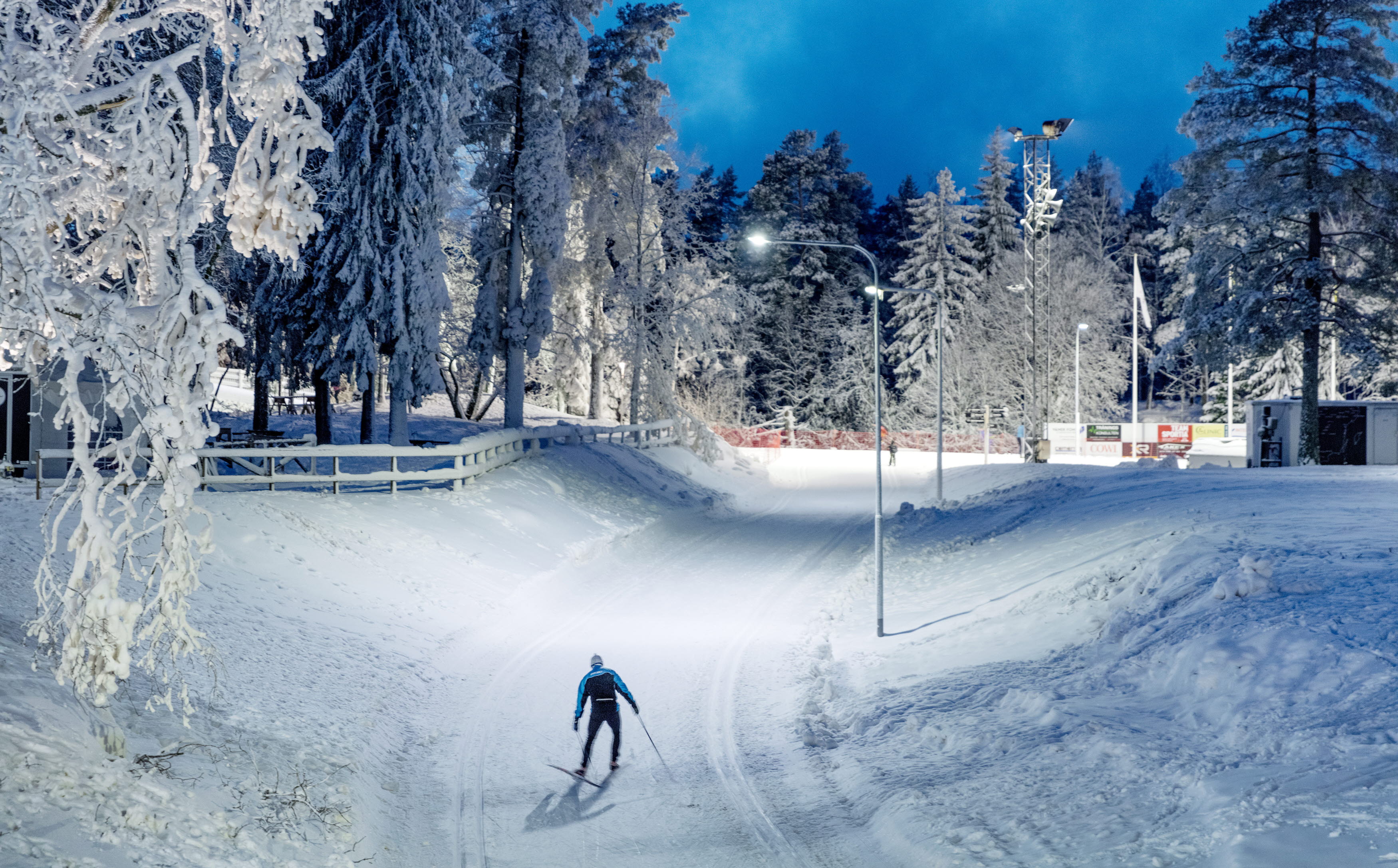 Skidåkare svischar förbi i spåren en vinterkväll på Billingen Skövde. 