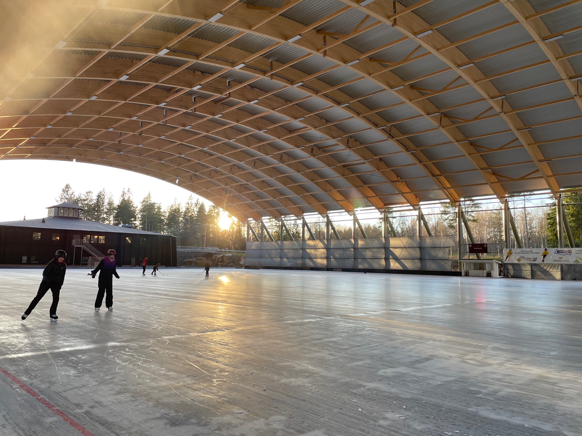 En isbana med tak utomhus. Två personer åker på isen.