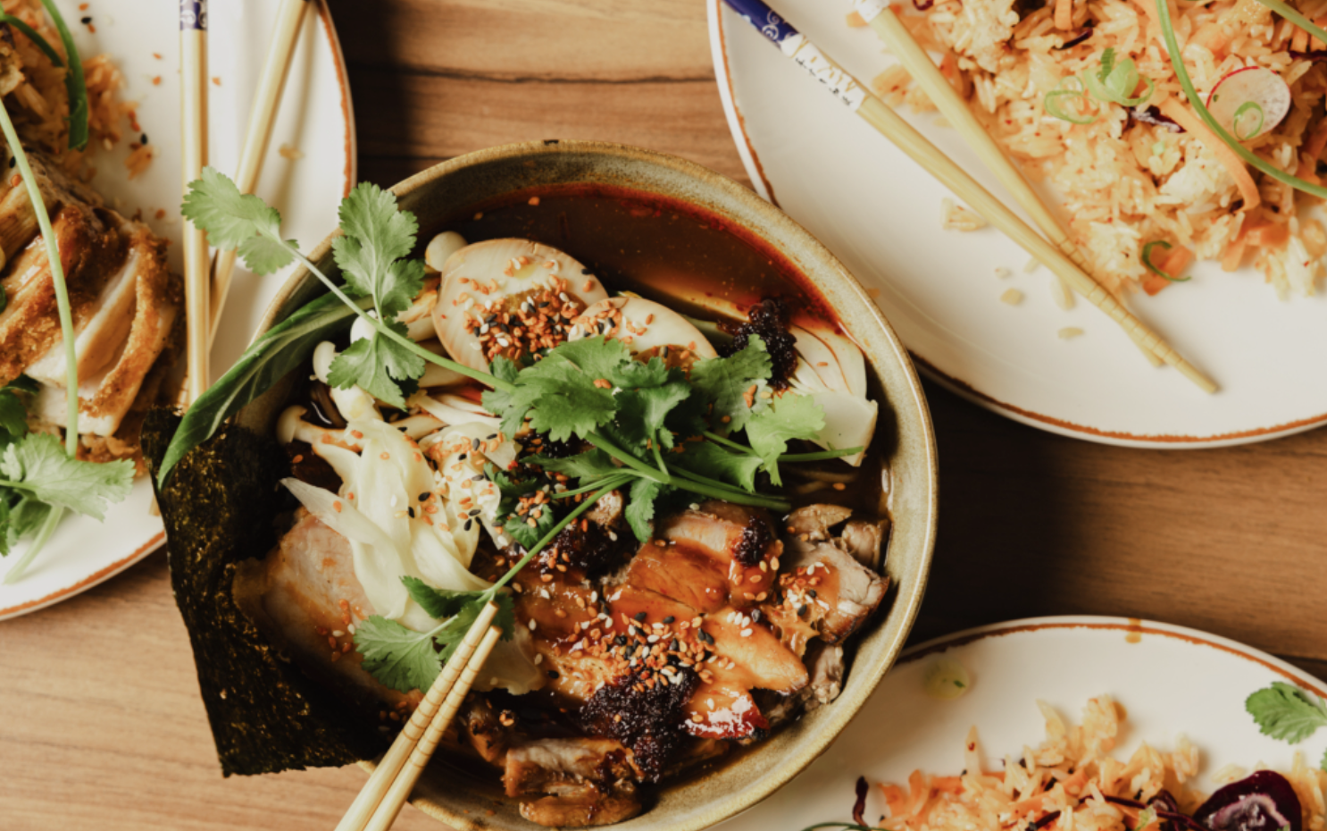 Flera tallrikar med olika maträtter på en träbord