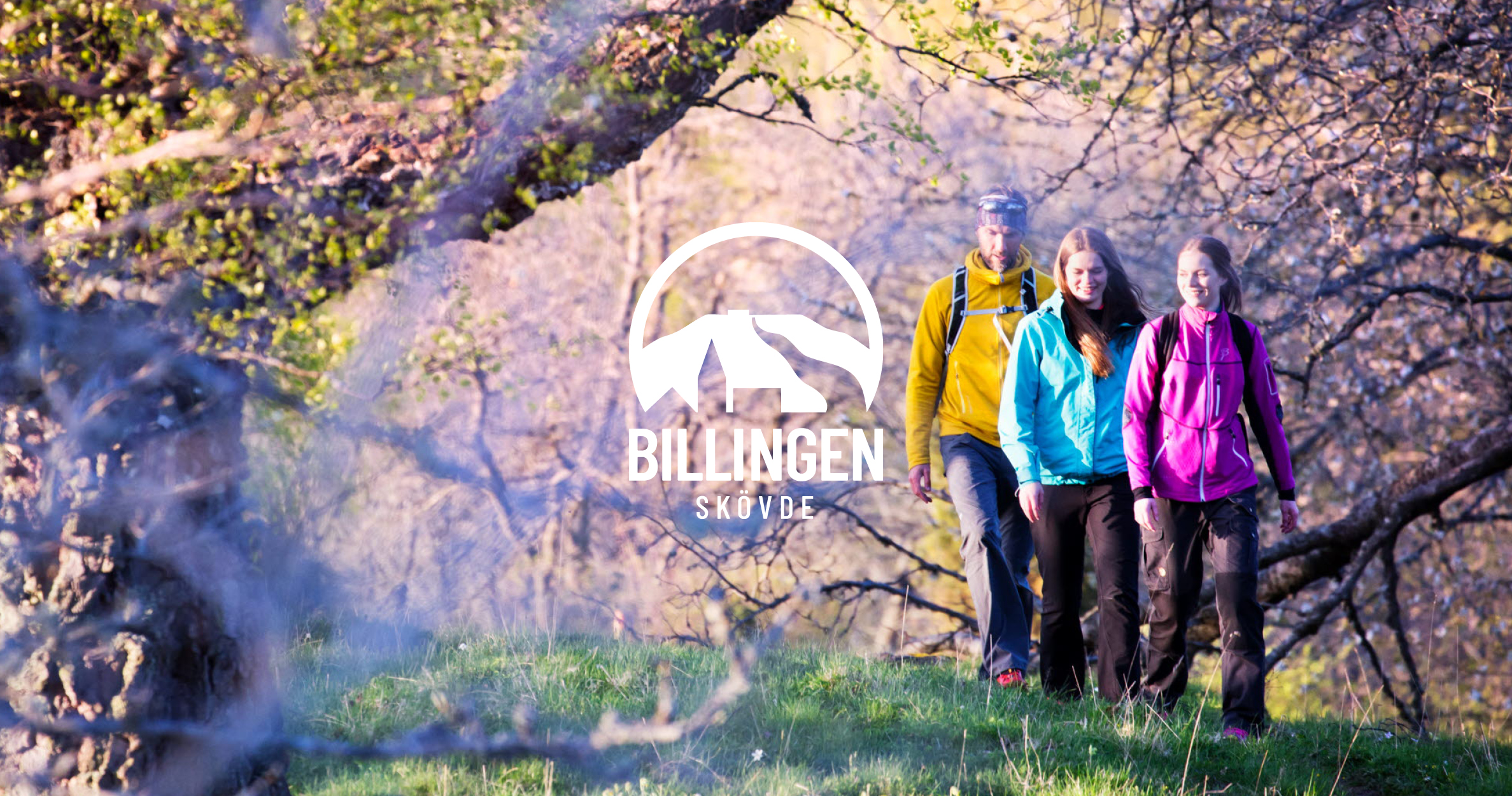 Tre vandrare under träd där löven håller på att spricka ut. 