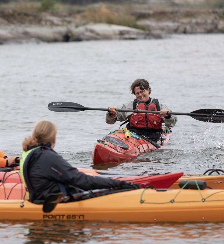 Kvinna som visar hur man paddlar för en grupp kajaktiser.