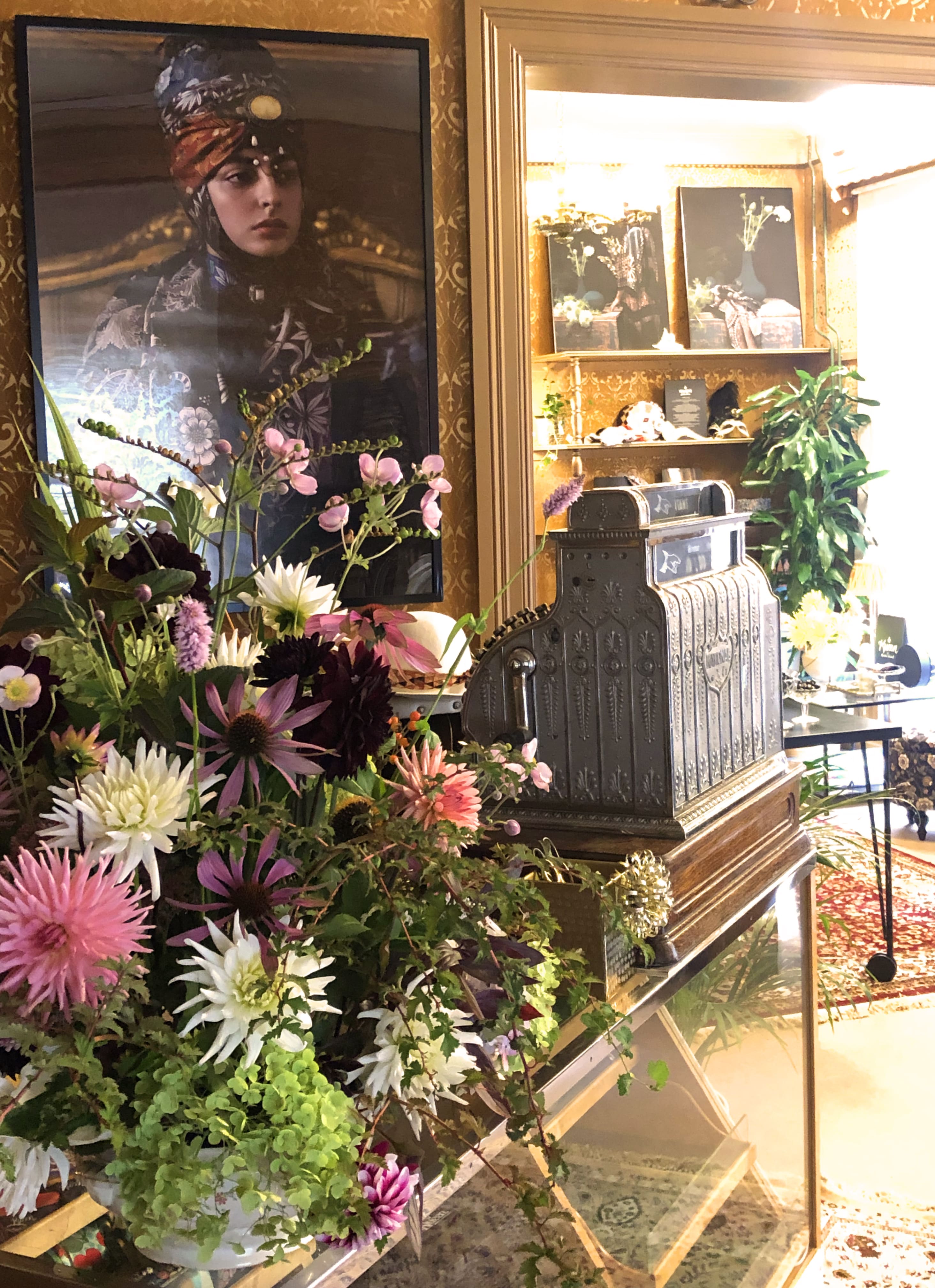 En gammaldags kassaapparat med blommor i förgrunden. 