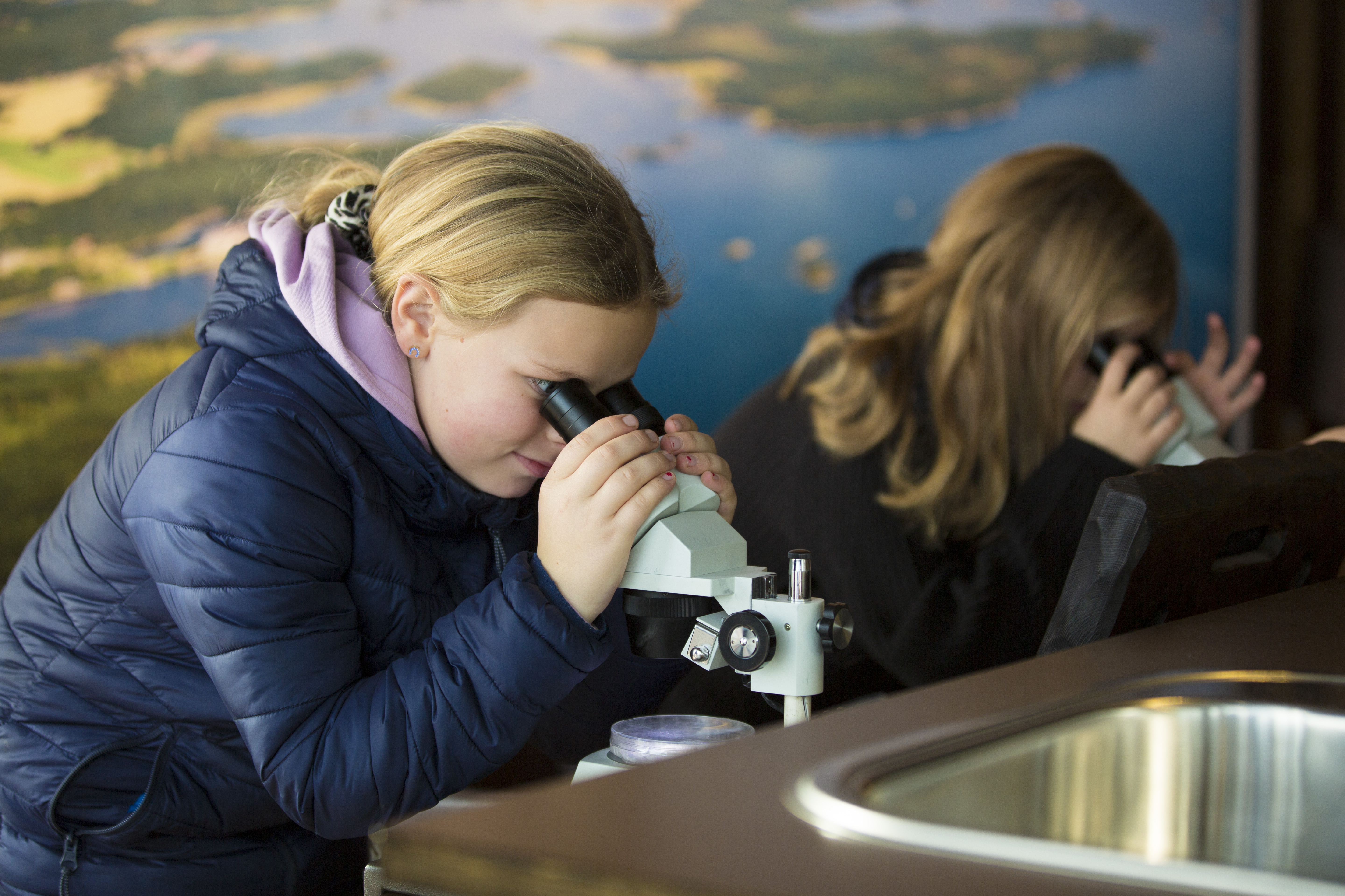 Två barn sitter och kollar i var sitt mikroskåp 
