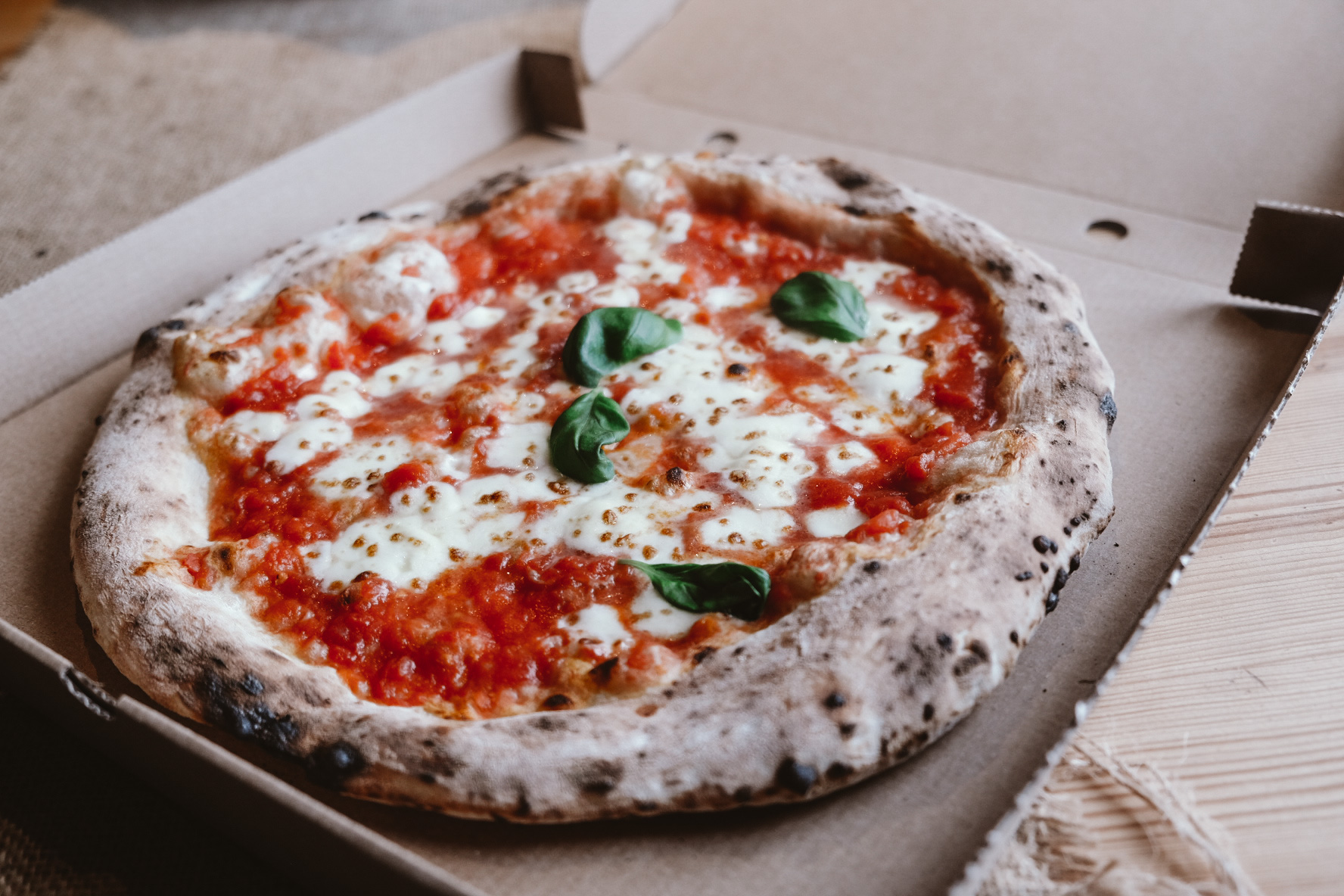 På bilden syns en pizza. Pizzan är vedugnsbakad. 