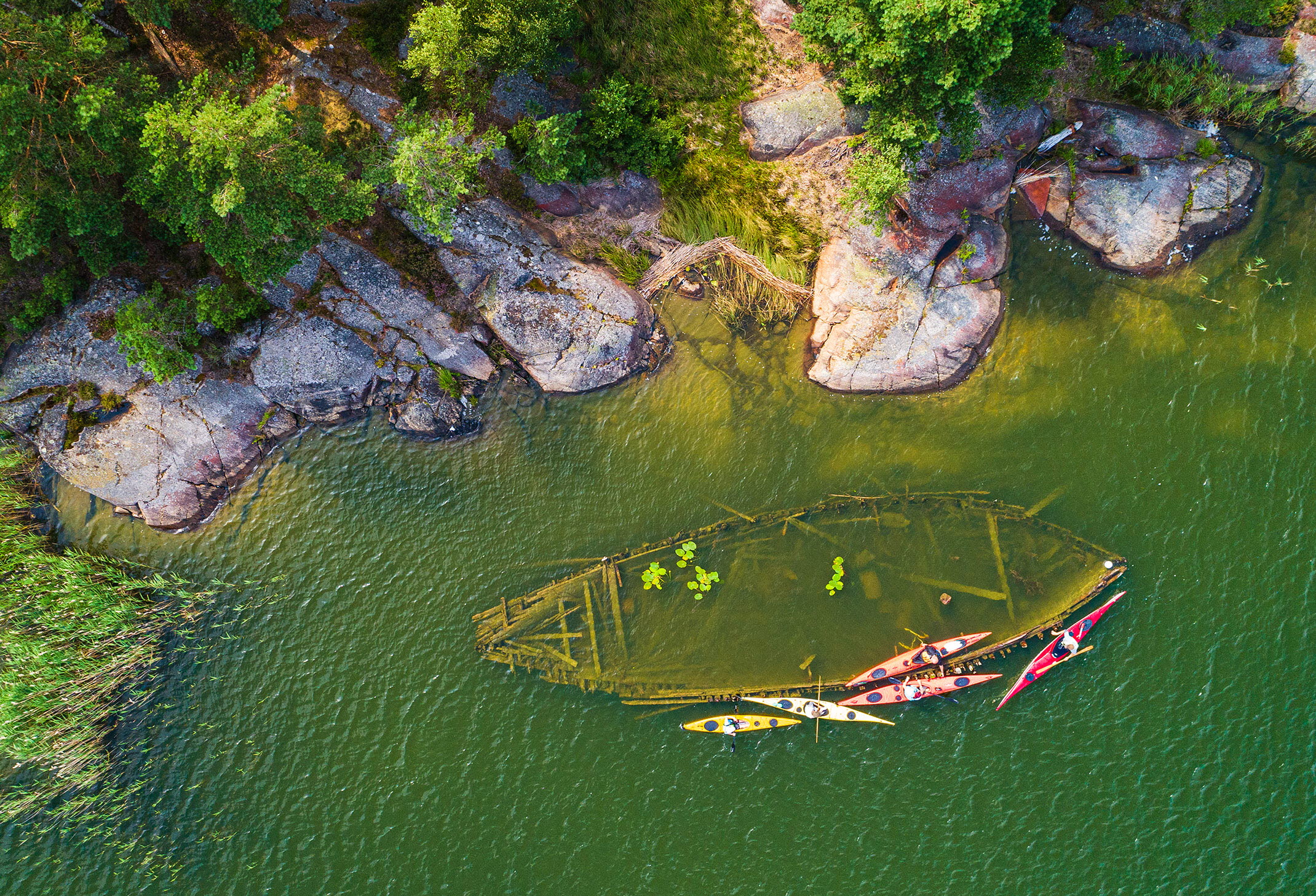 Ett vrak som ligger nära land i vattnet. Det syns ovanifrån.