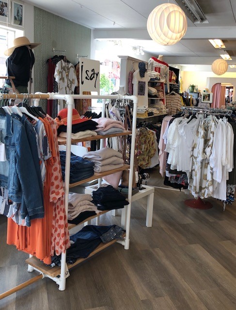 En butik med kläder på hyllor och på ställningar