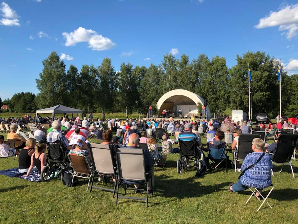 Massa människor som sitter på en grön gräsmatta. 