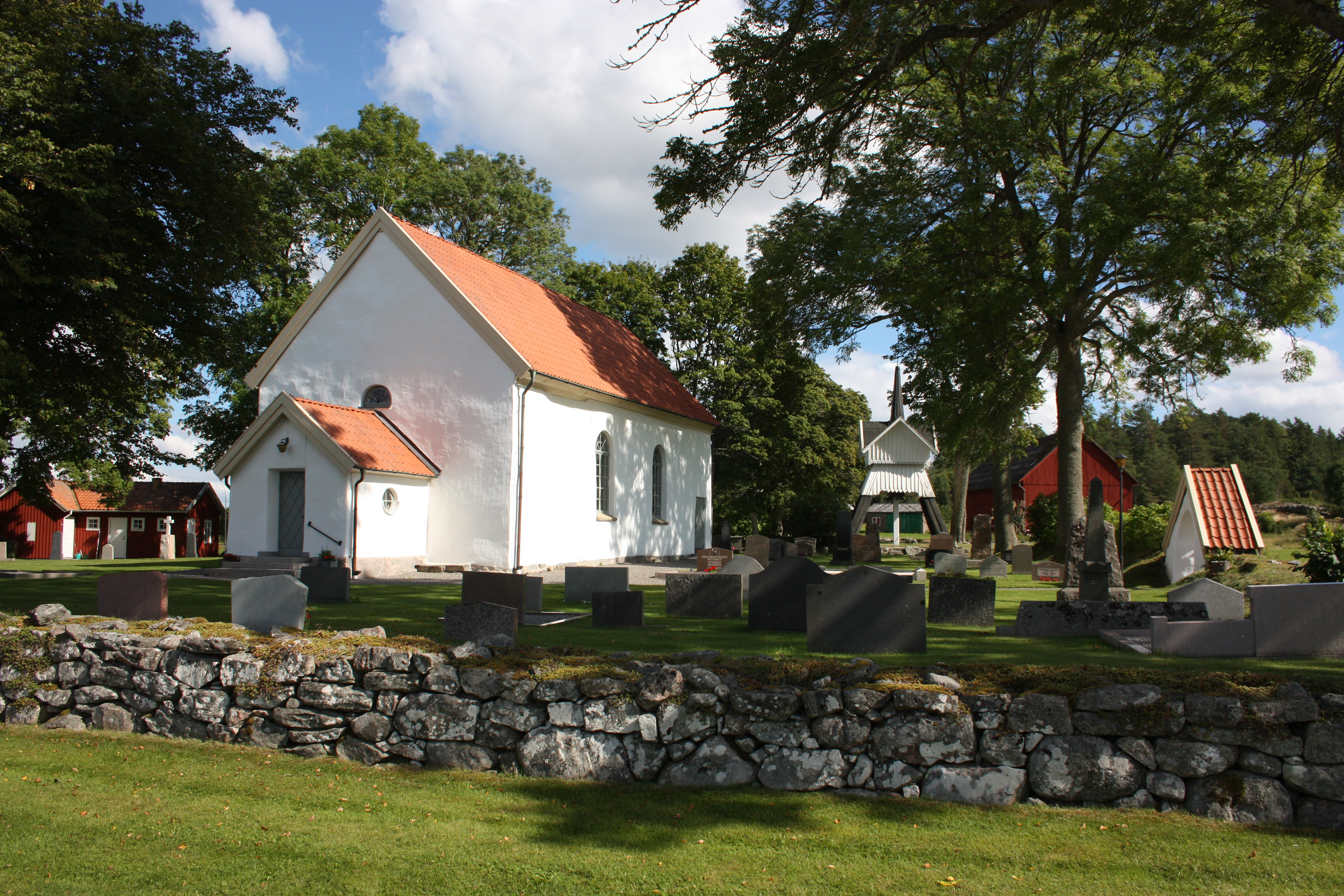 en vit träkyrka med en stenmur framför