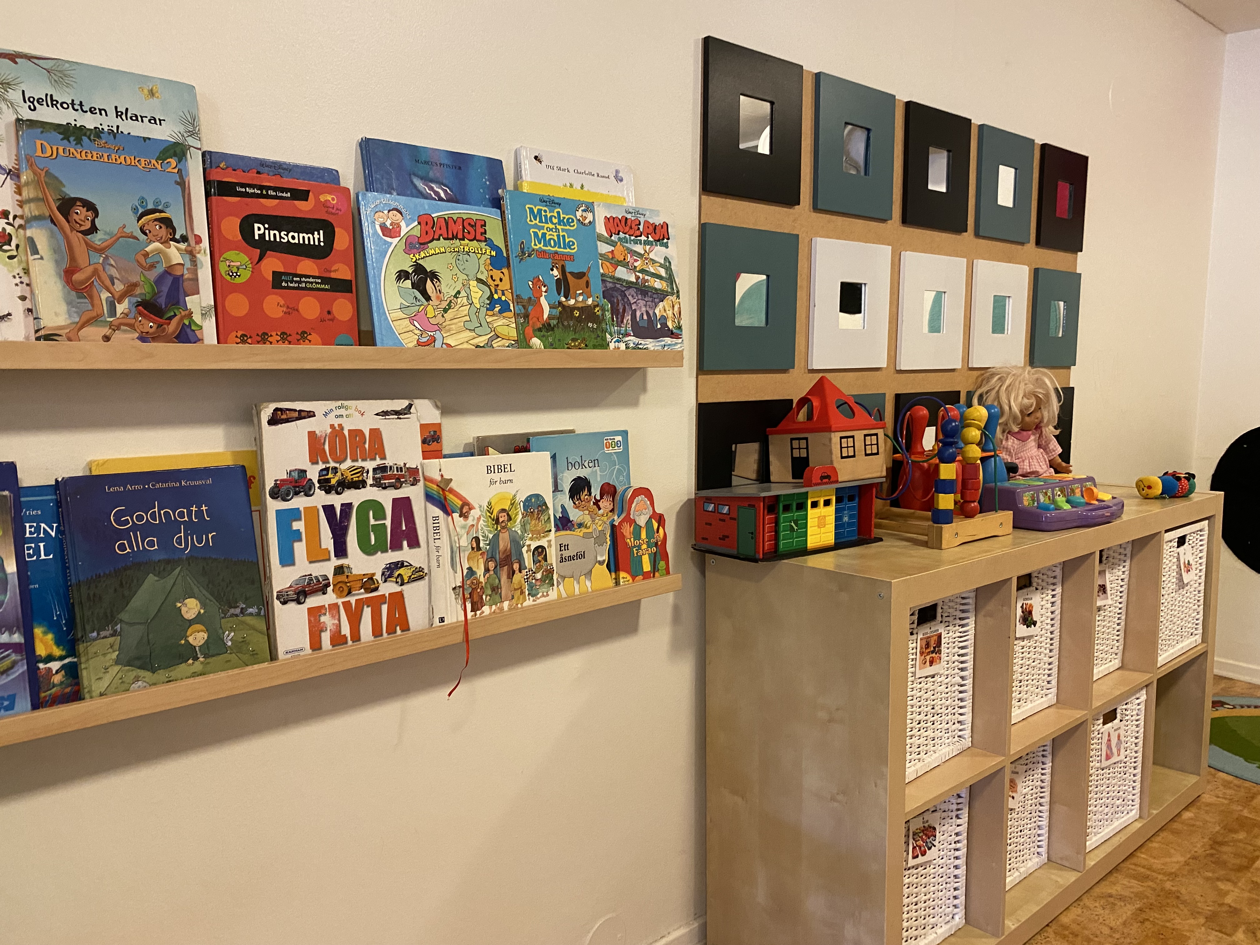 Lekhörna med böcker och en hylla med leksaker på. 