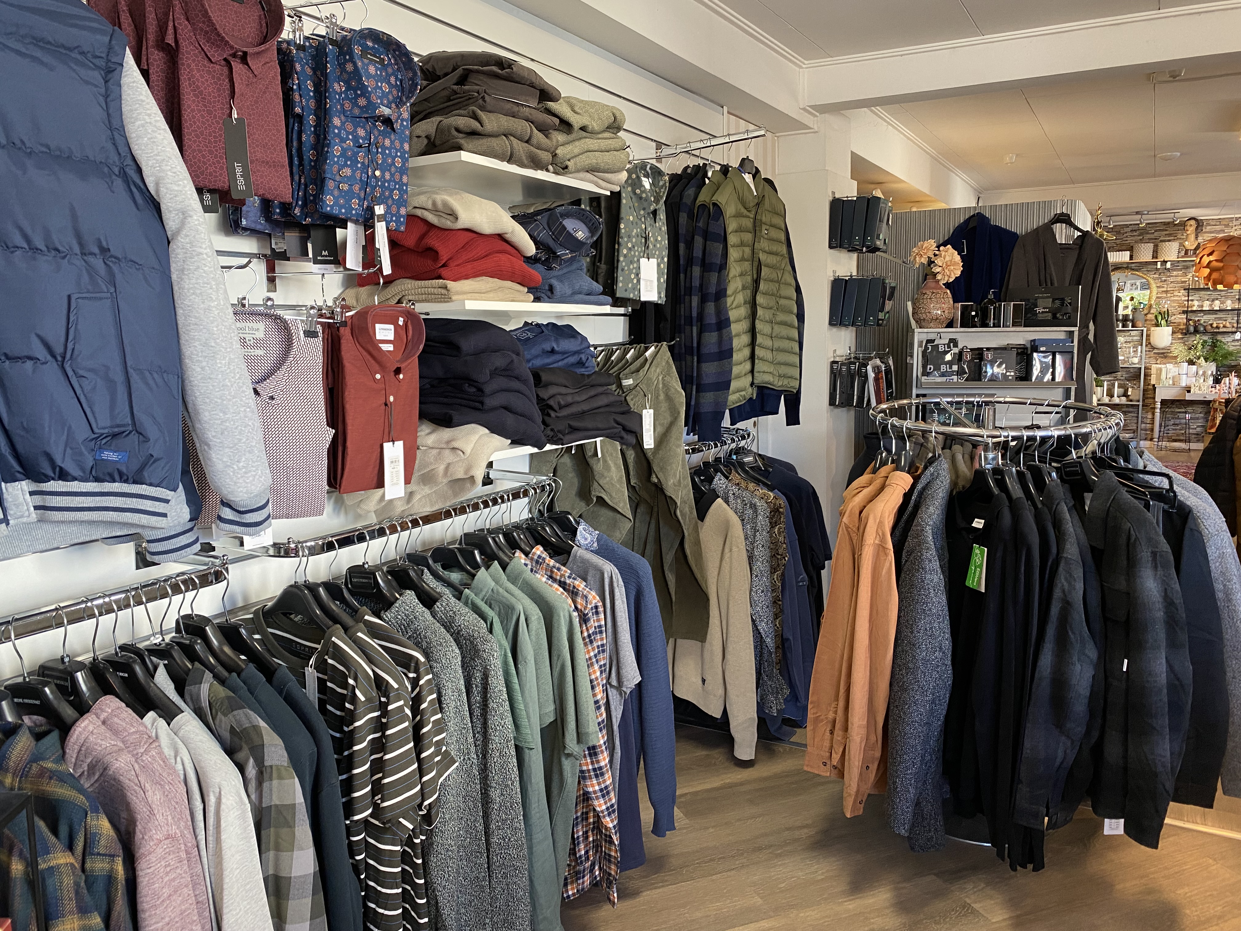 Herrkläder i en klädbutik som hänger på ställningar. 
