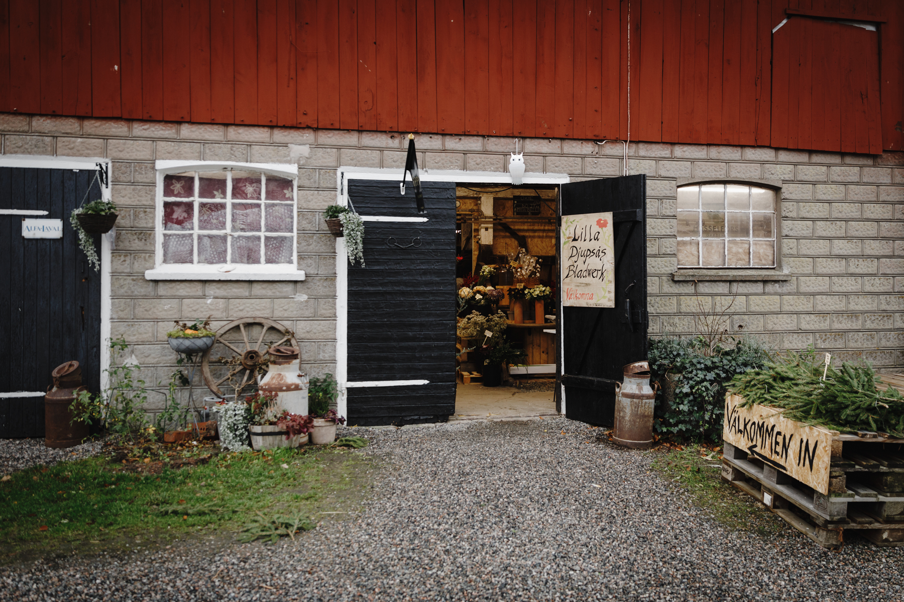 En ladugård med svarta dörrar, en av dem är öppen och därinne finns en butik.