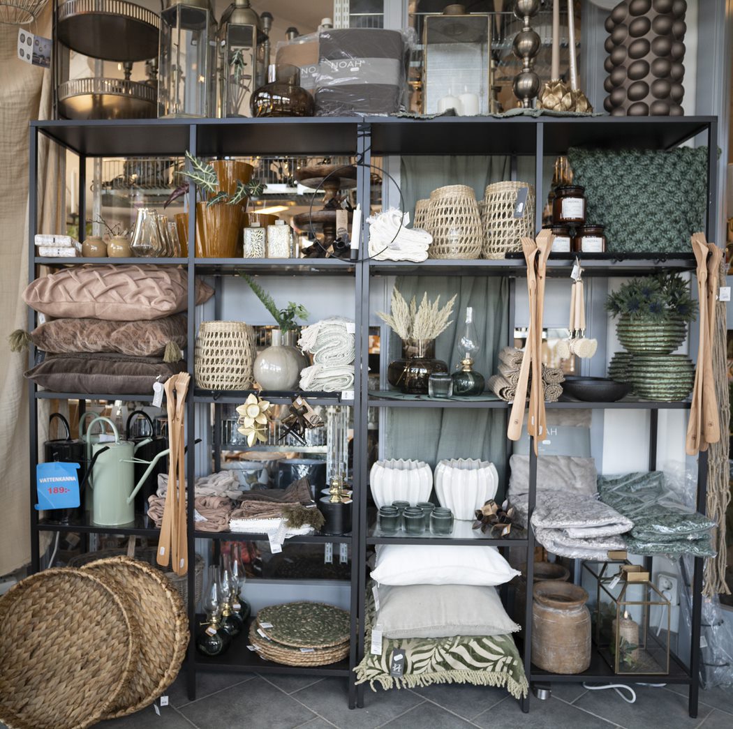 Inredningssaker som står på hyllor. Massa olika saker som ljusstakar, kuddar, vattenkannor och lampor. I dova färger. 