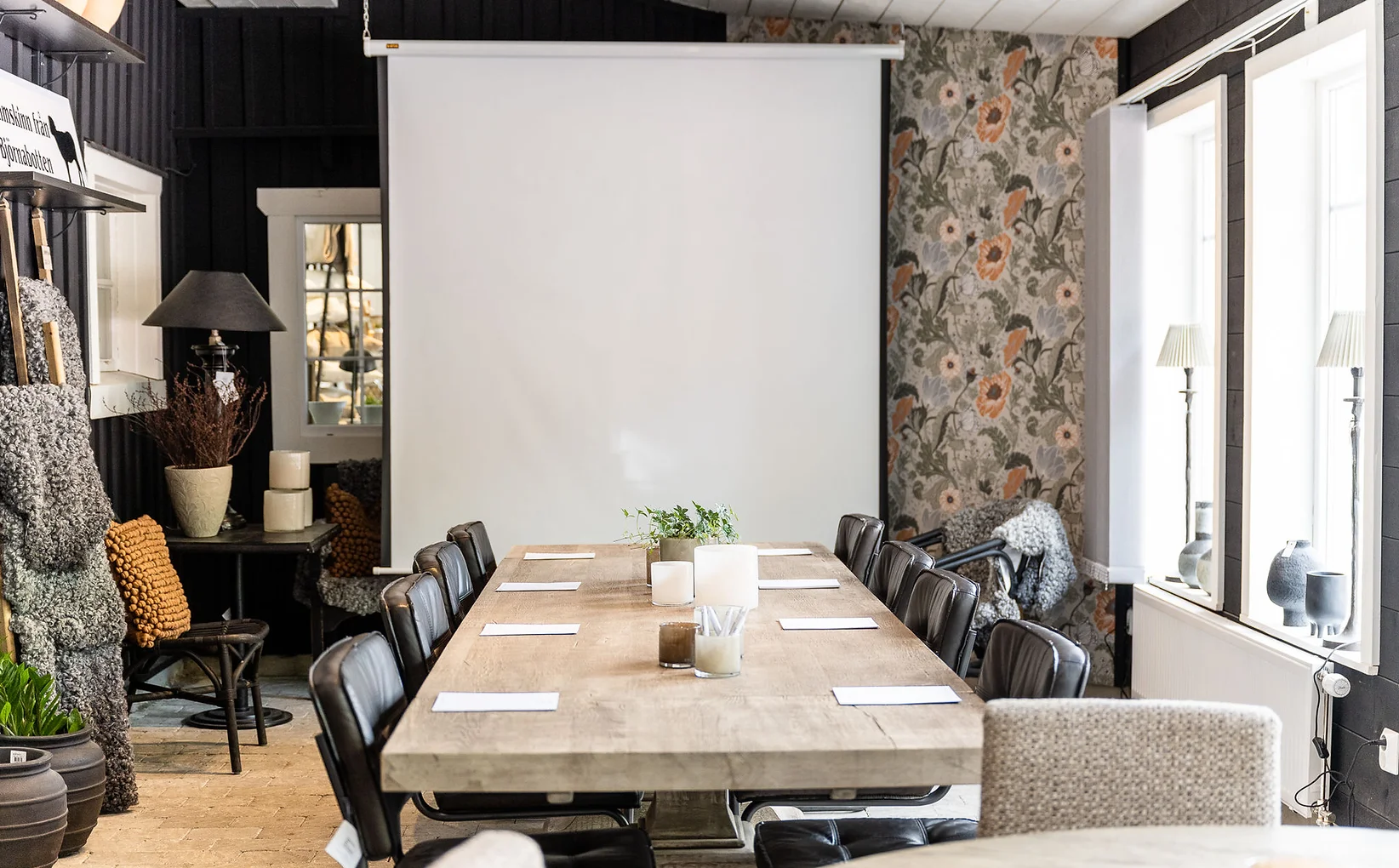Stolar som står runt ett bord med en vit projektduk bakom. 