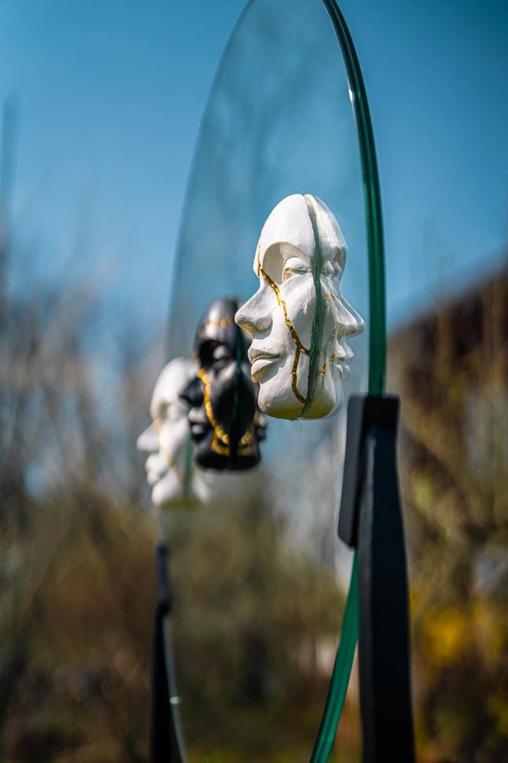 tre ansikten i keramik på en glasskiva.