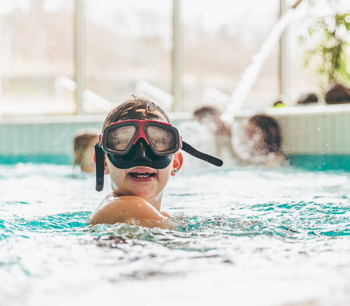 Pojke med cyklop som är i poolen.