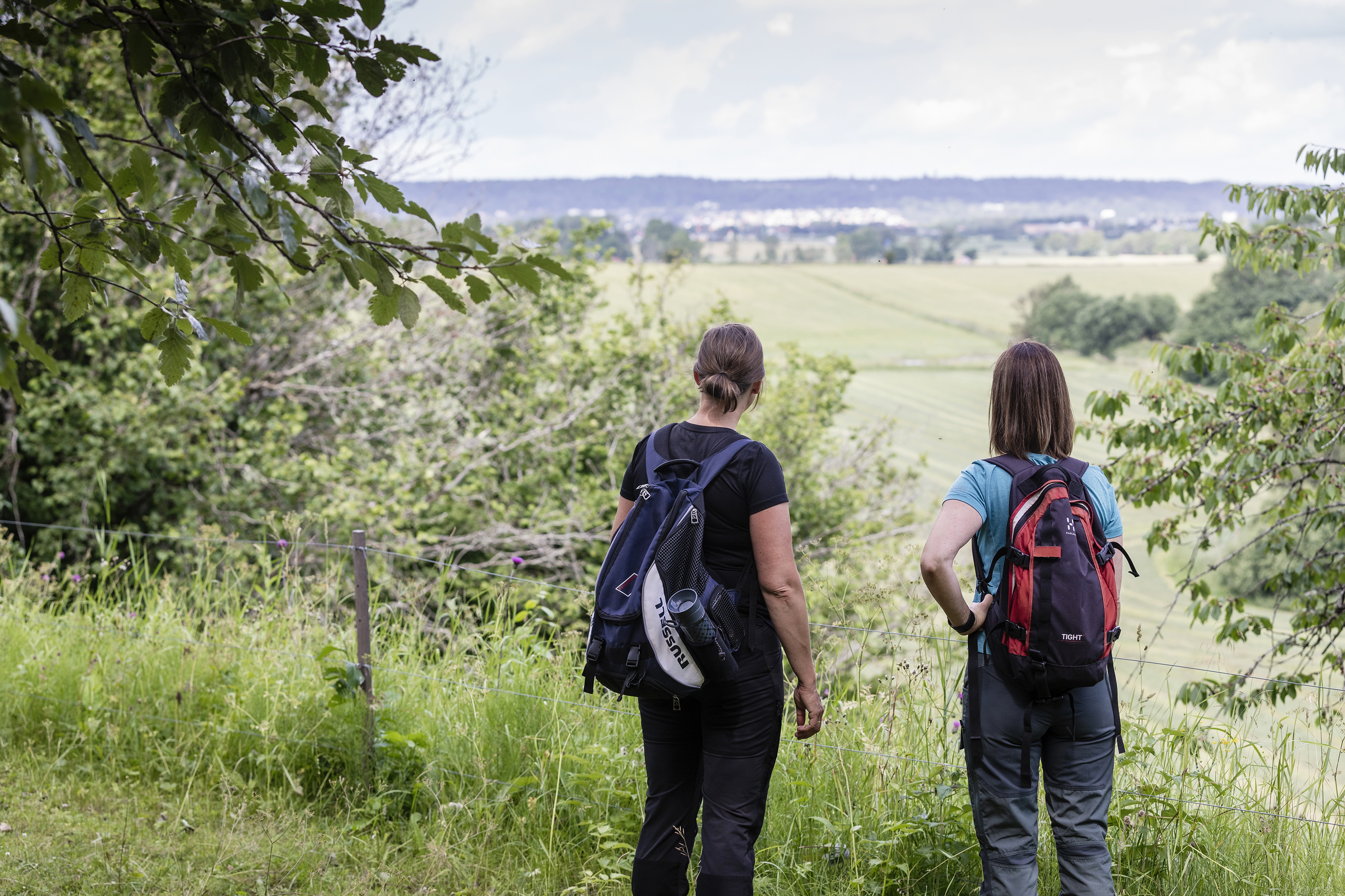 Två kvinnor i vandringskläder står och kikar på utsikten.