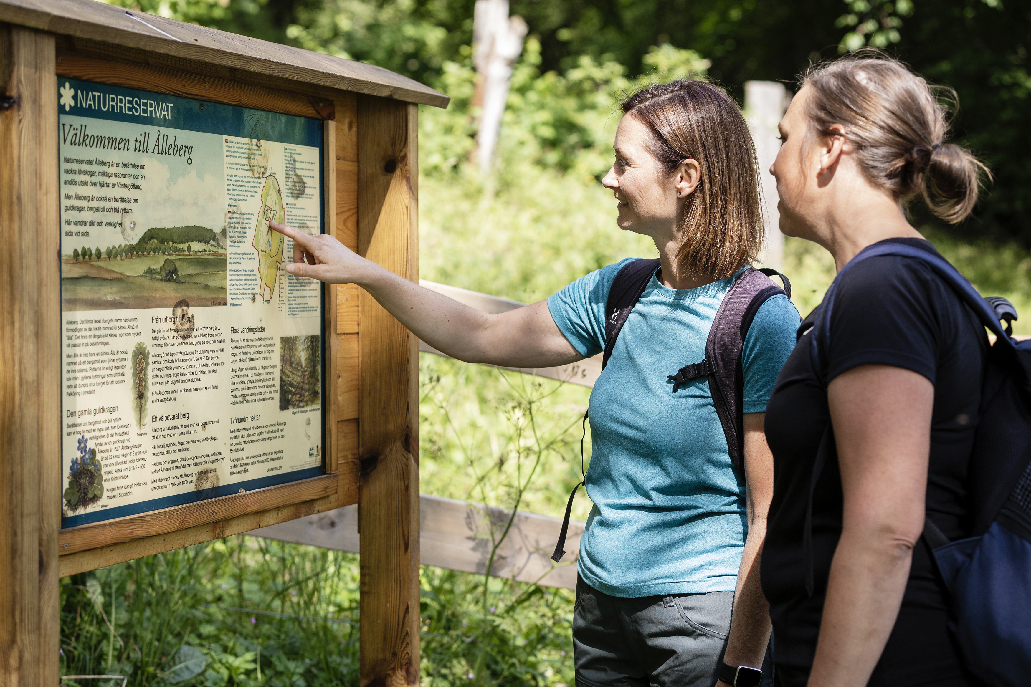 Två kvinnor står och läser på en skylt om naturreservatet.