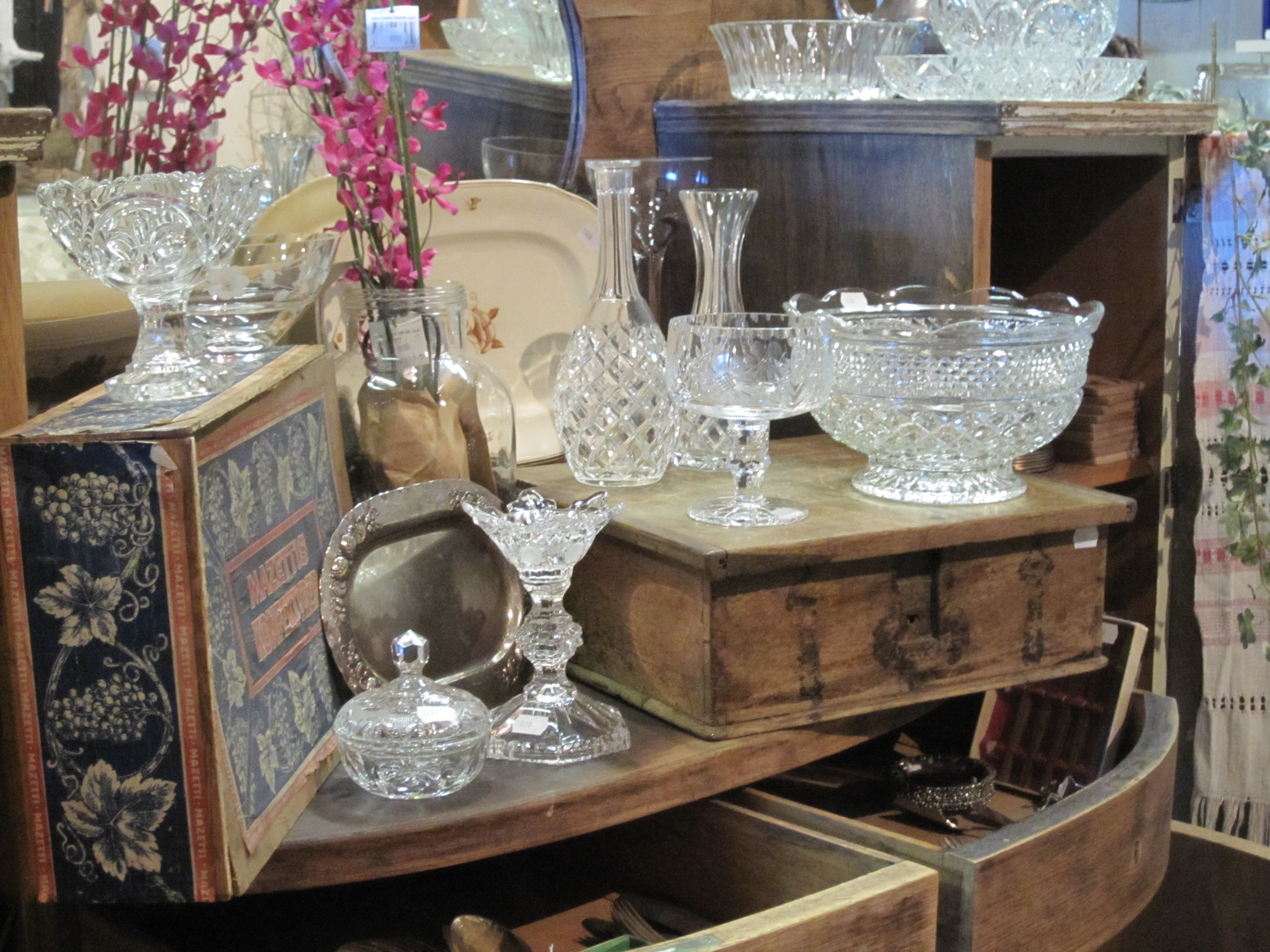 Antikbutik med glas skålar och vasar på träbord.