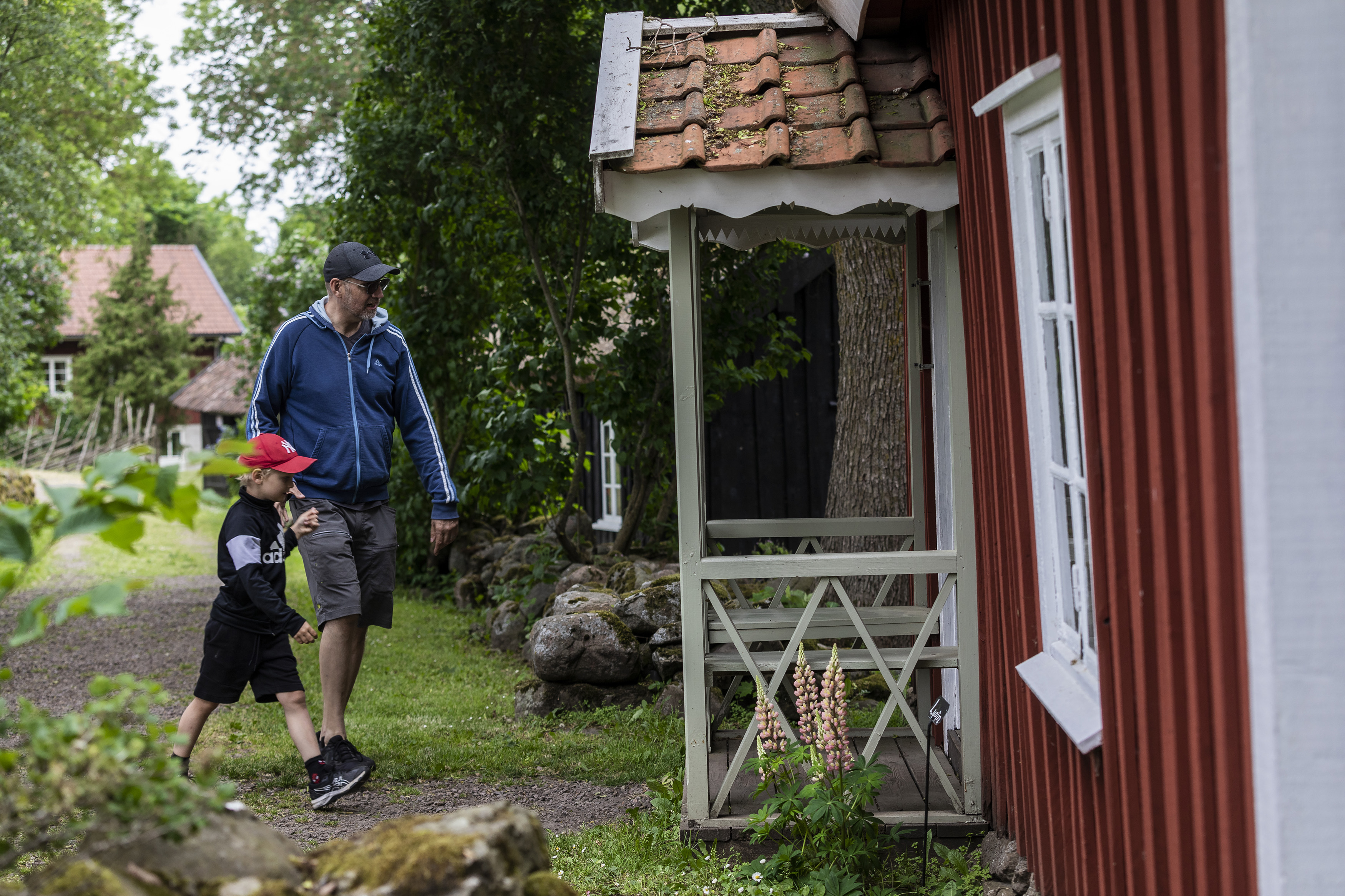 Pappa och en pojk är på väg in i en röd stuga.