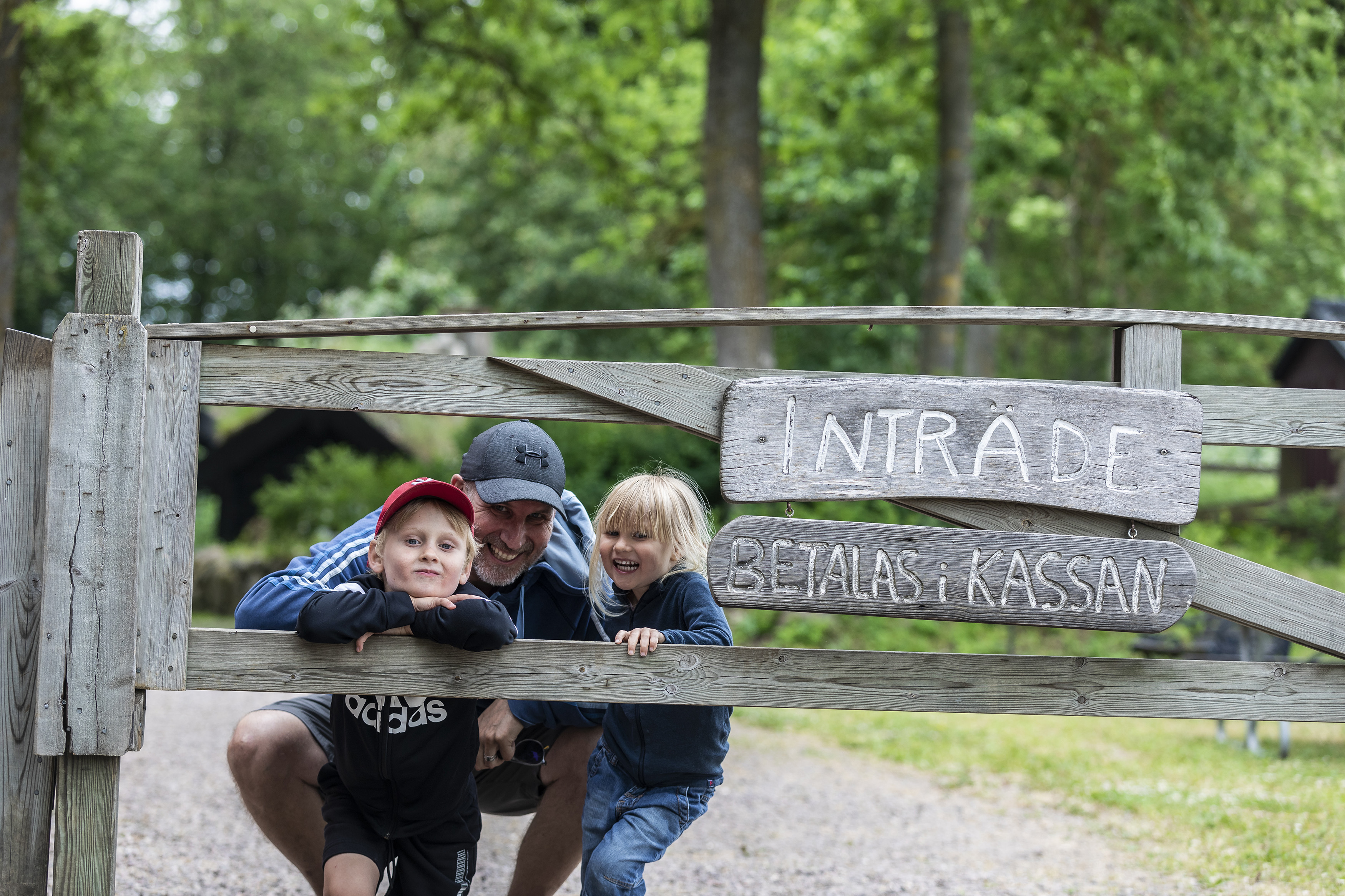 Dad with two children peeks through a wooden gate.